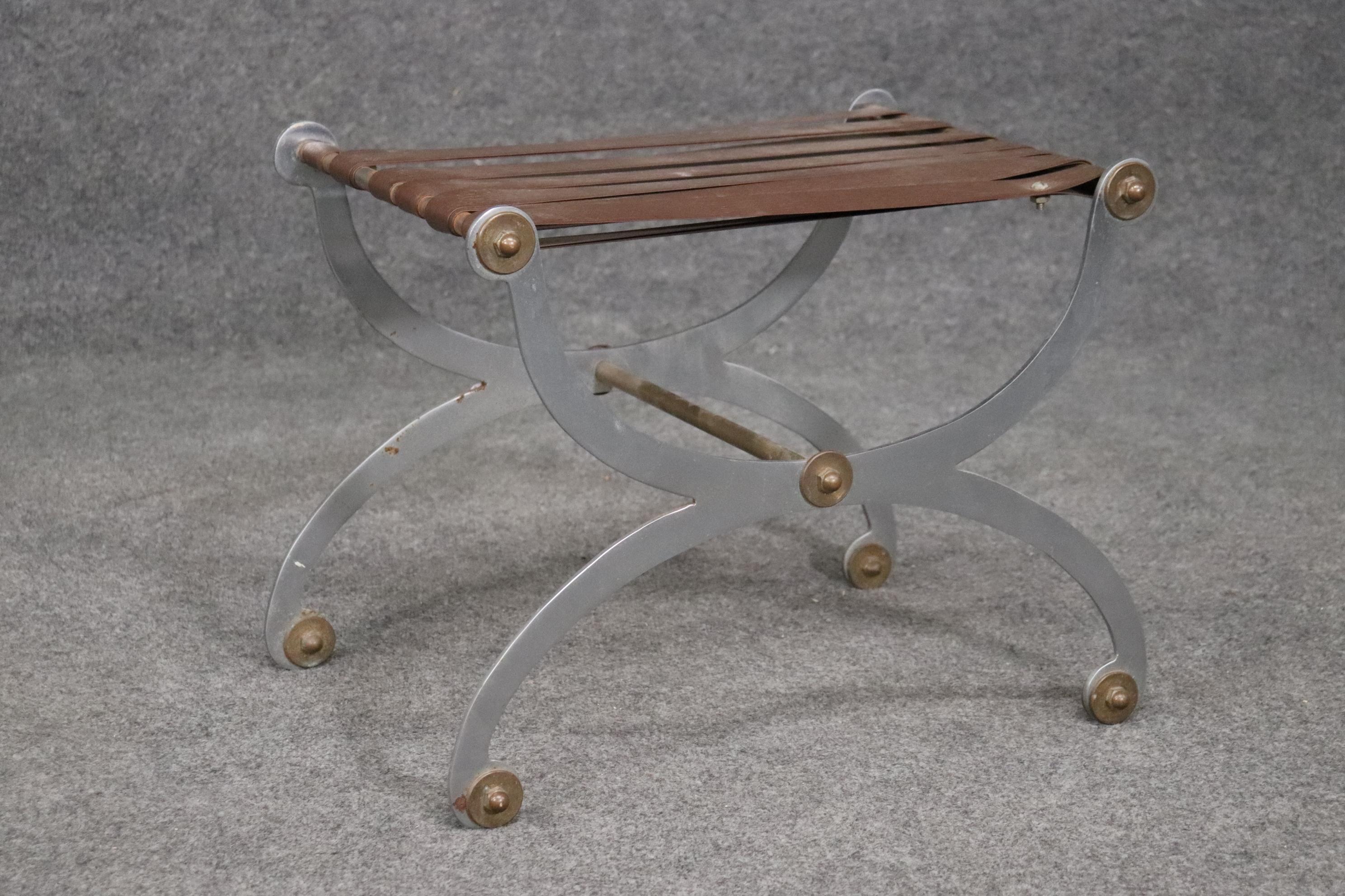 This is a sophisticated Maison Jansen attributed foot stool. The stool is supposed to have a cushion on top of the vinyl webbed supports. The piece has brass and steel elements and is a true icon. Measures 16 deep x 22 wide x 17 tall.