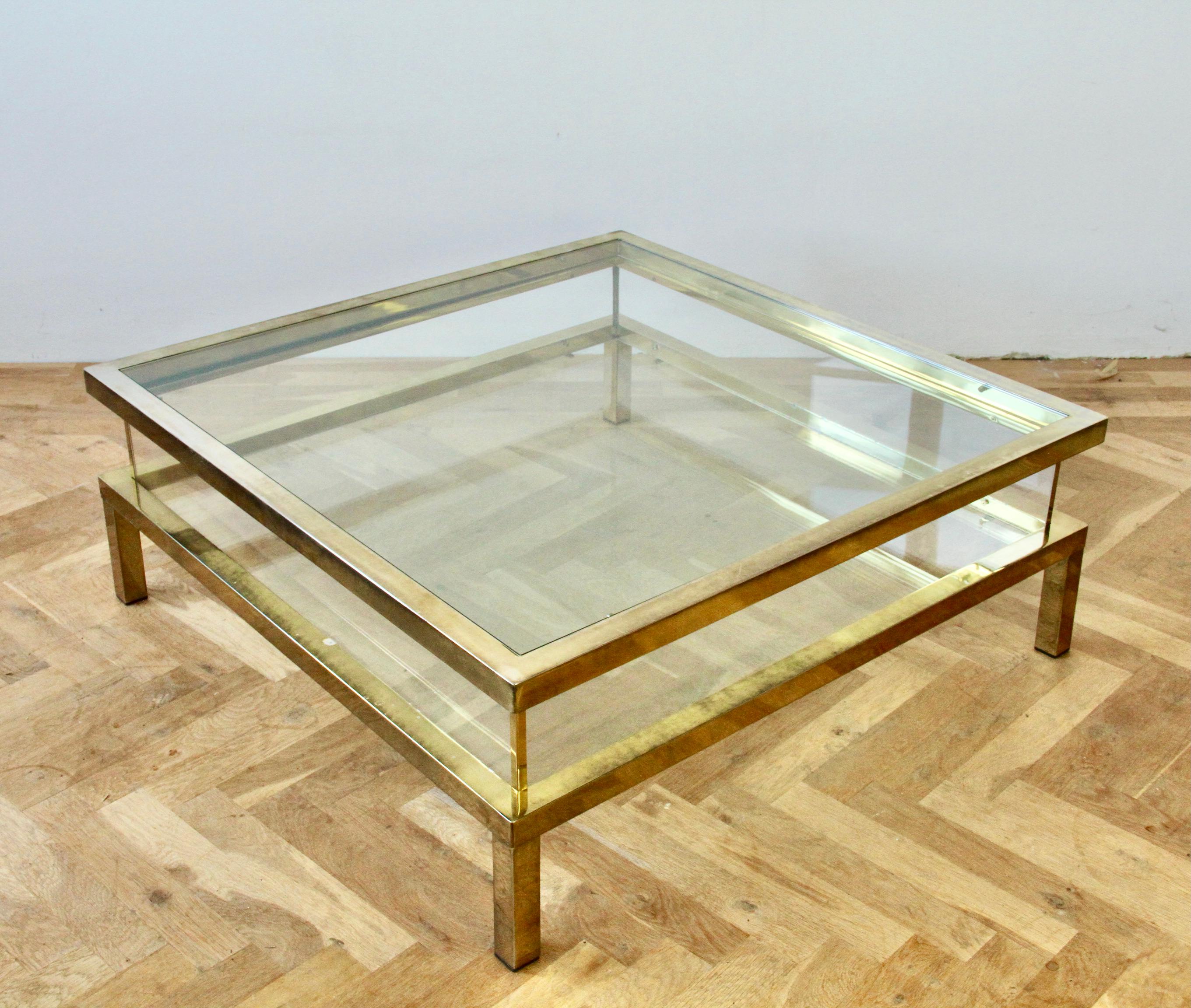 Stunning vintage Mid-Century Modern square vitrine coffee table in polished brass with sliding glass tabletop and acrylic / Lucite side walls in the style of Maison Jansen, circa 1970s. Perfect for the Hollywood Regency style enthusiast or