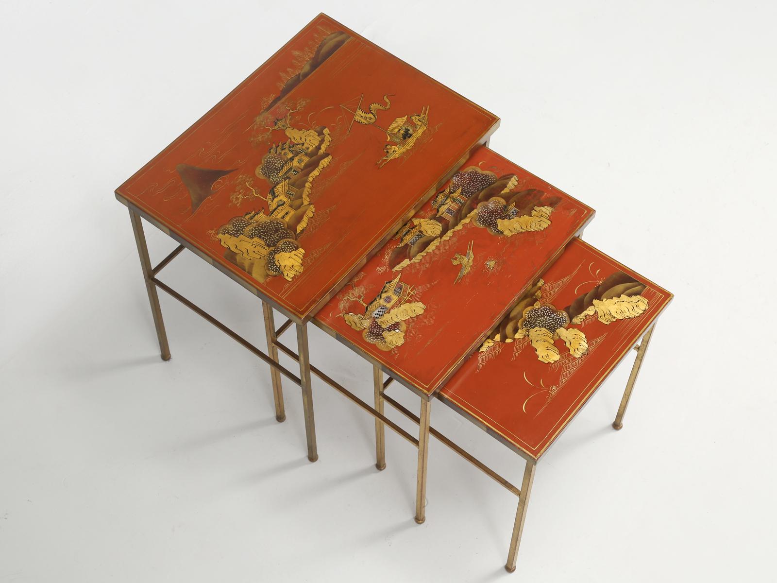Maison Jansen (attributed to by French expert) set of three nesting tables with red and gilt lacquered tops. The decoration or paintings are of landscapes in China. Please note that the red is slightly different on each of the stacking tables, which