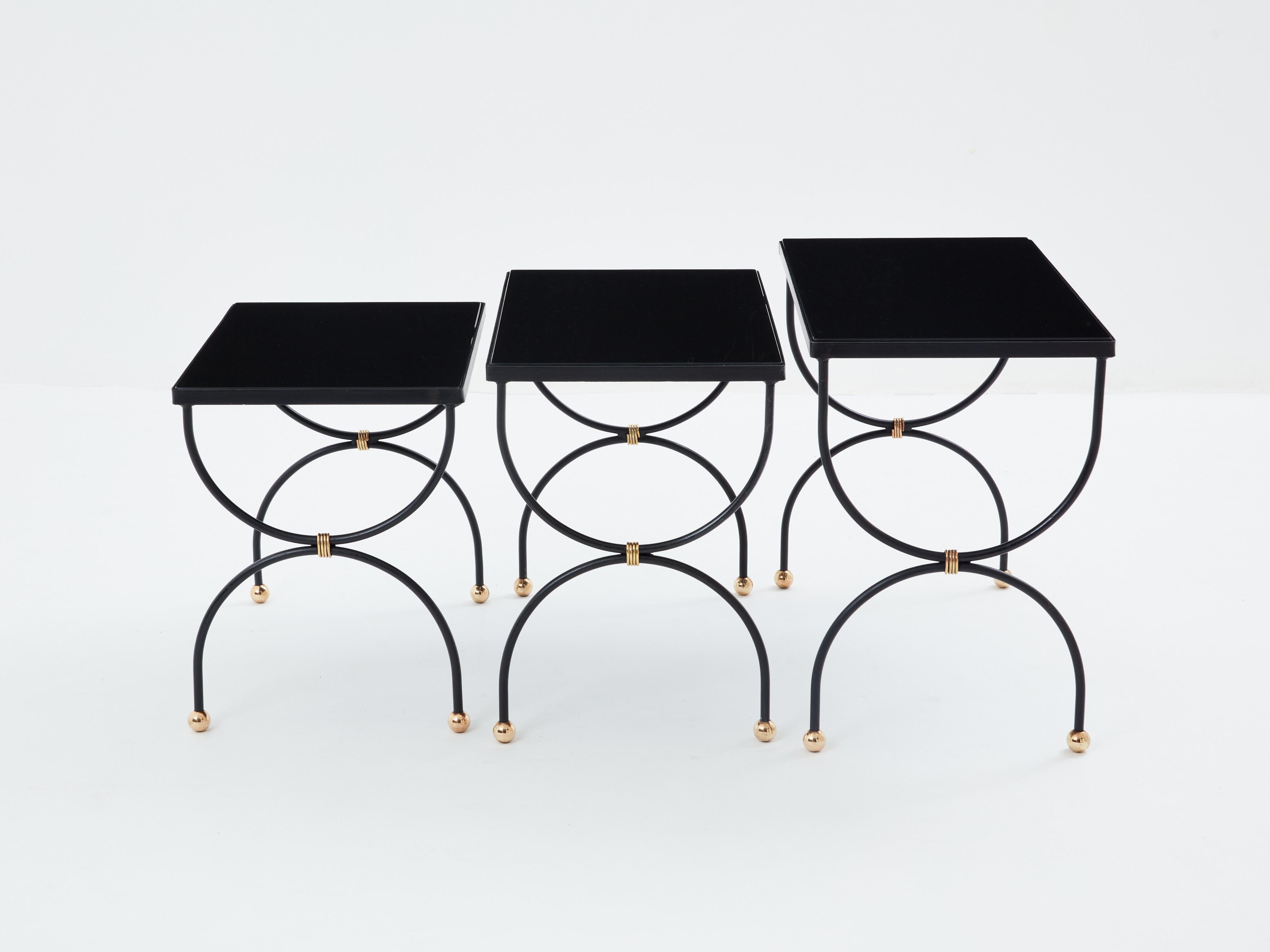 Ces tables gigognes en fer noir et laiton, fabriquées par la Maison Jansen au début des années 1960, confèrent à votre intérieur une véritable élégance. Chaque table est dotée d'un plateau noir opalin et de magnifiques détails en laiton. Ce sont de