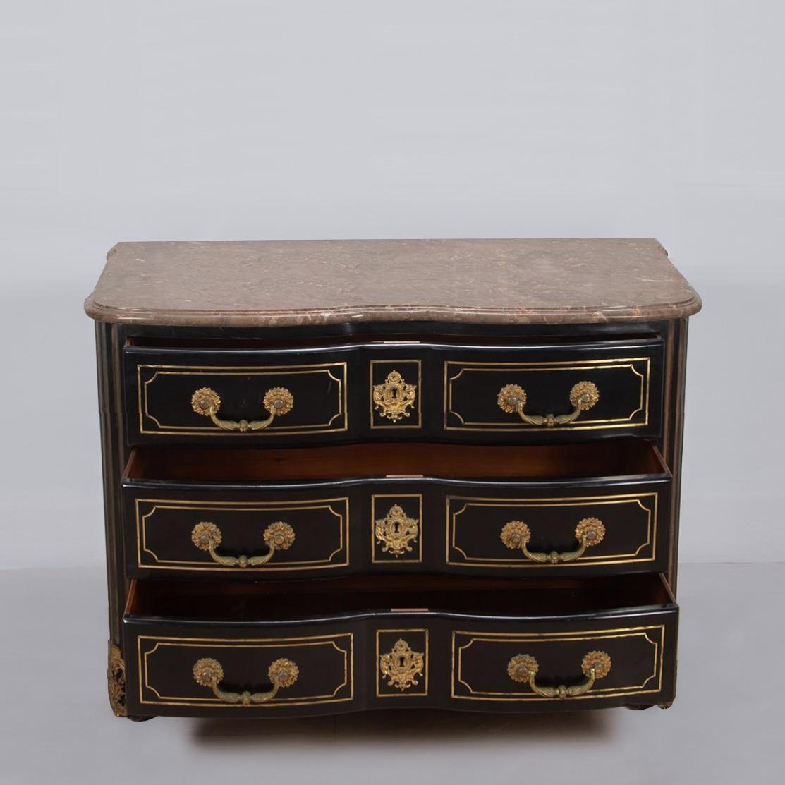 Una raffinata e rara commode con piano in marmo intarsiato in ottone e ormolu della Maison Jansen, in stile Regence, degli anni '40 circa. 

Il piano in marmo sagomato con un sottile bordo a doppia modanatura, poggia su una base laccata nera lucida