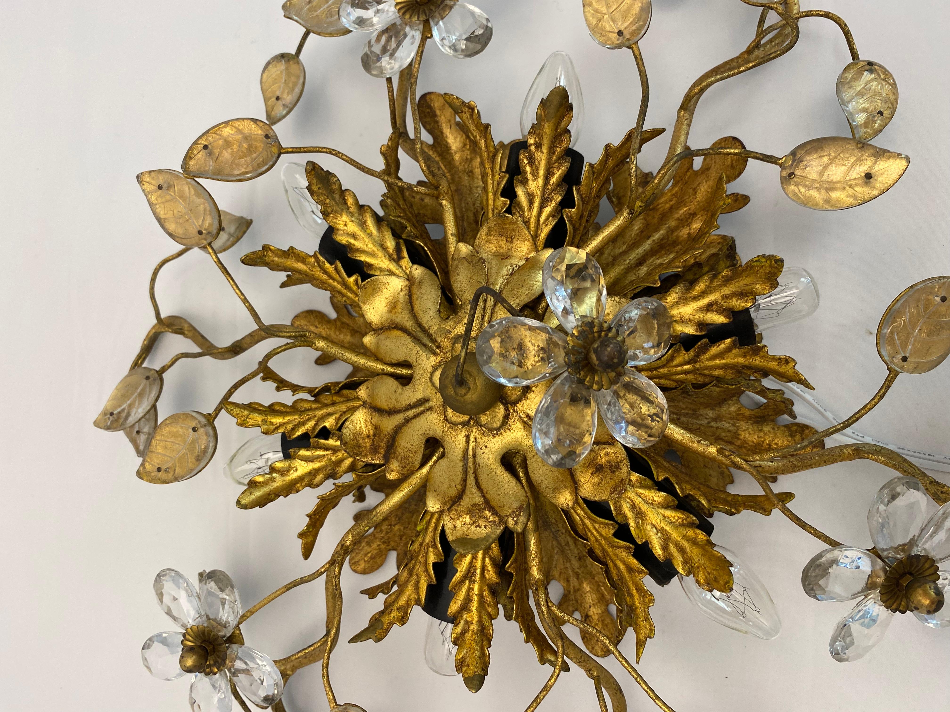 Iconic wall sconce manufactured by Maison Jansen, design attributed to Hans Kogl.  This Gilt Iron Ornate Wall Light or Ceiling Light Fixture possesses and outstanding design.  Hand-hammered gilt iron ornate details, brass and crystal floral shaped