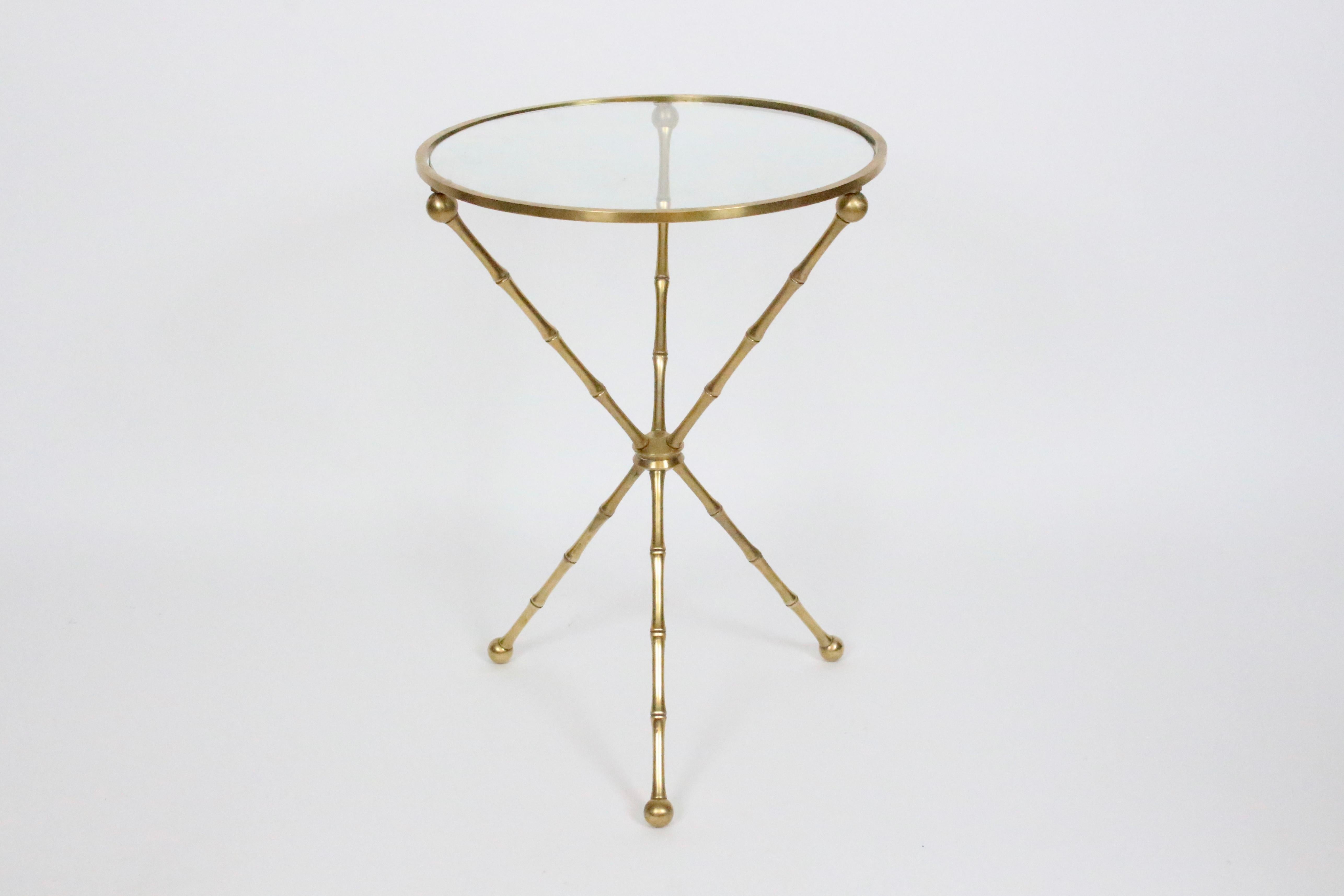 Maison Jansen attributed Tripod Brass Faux Bamboo Occasional Table. Drinks. Plants. Display. Accent. Featuring a molded and reinforced reflective solid Brass tripod base, Brass rimmed top inset with circular .25H glass and ball detail, tri faux