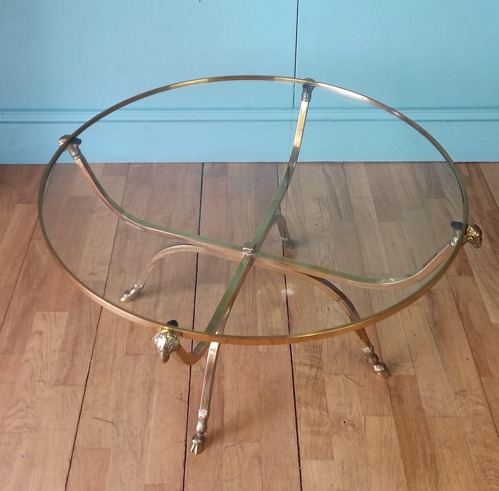 Original French coffee table circa 1960's designed by the Paris based interior design house of Maison Jansen.
Solid brass frame with decorative rams head finials and hoof feet to all four legs supporting circular glass top.
In lovely aged original
