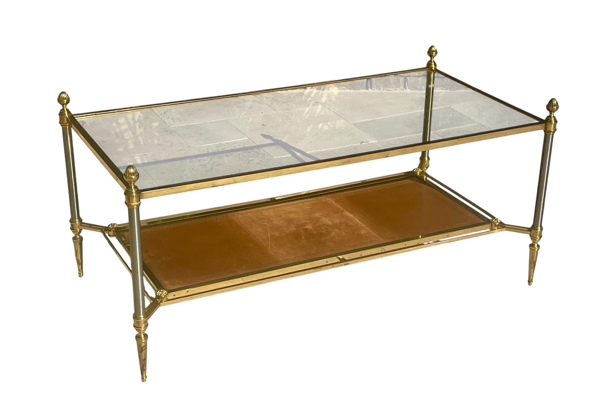 Table basse en laiton doré de la Maison Jansen. Il est doté d'un plateau en verre et d'un plateau en cuir de couleur cognac. Cette table est en bon état. Circa 1940 
 
 Dimensions 
 Hauteur 48,5 cm
Largeur 53cm
 Longueur 1m03 
Hauteur entre les 2