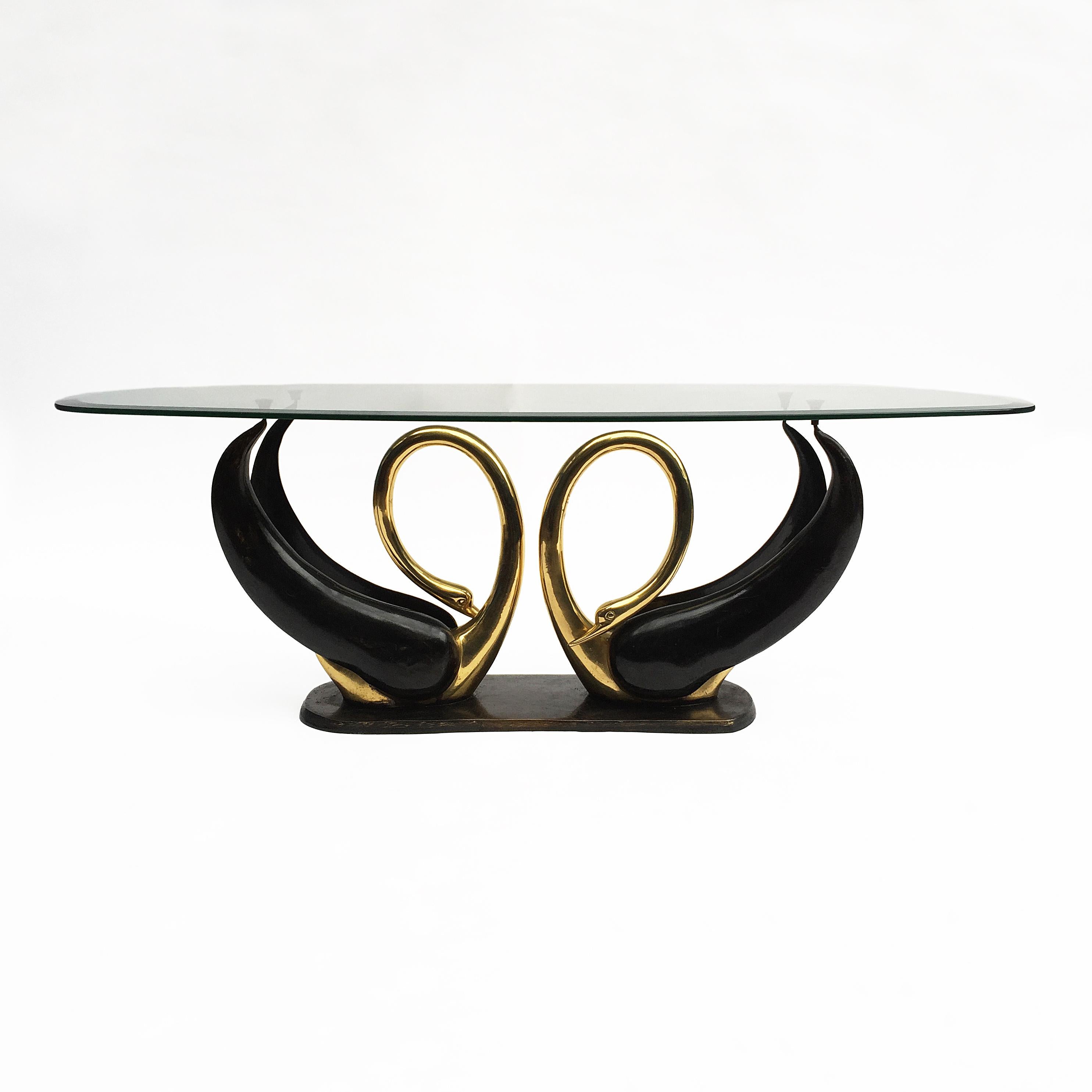 A beautiful love swans brass sculptured coffee table by Maison Jansen. Part of the body and brass base is black patinated and the rest polished brass. Amazing Hollywood Regency statement piece with a large rounded beveled glass top.
    