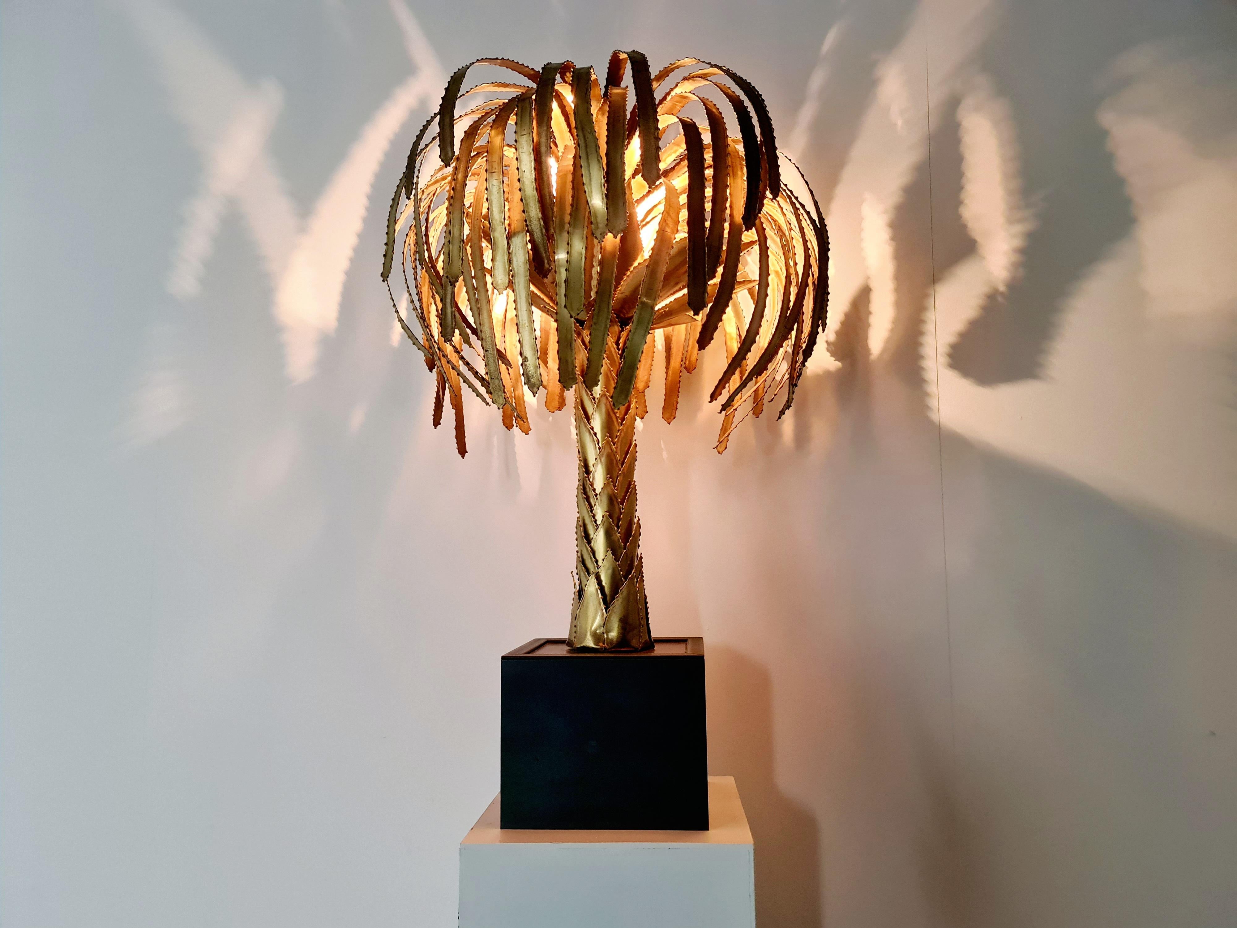 Highly decorative Maison Jansen palm tree lamp, France, 1960s. Torch cut patinated brass trunk and leafs coming out of a square black laminated heavy base. Hidden in the treetop are three bulbholders, they provide a warm light reflecting on the