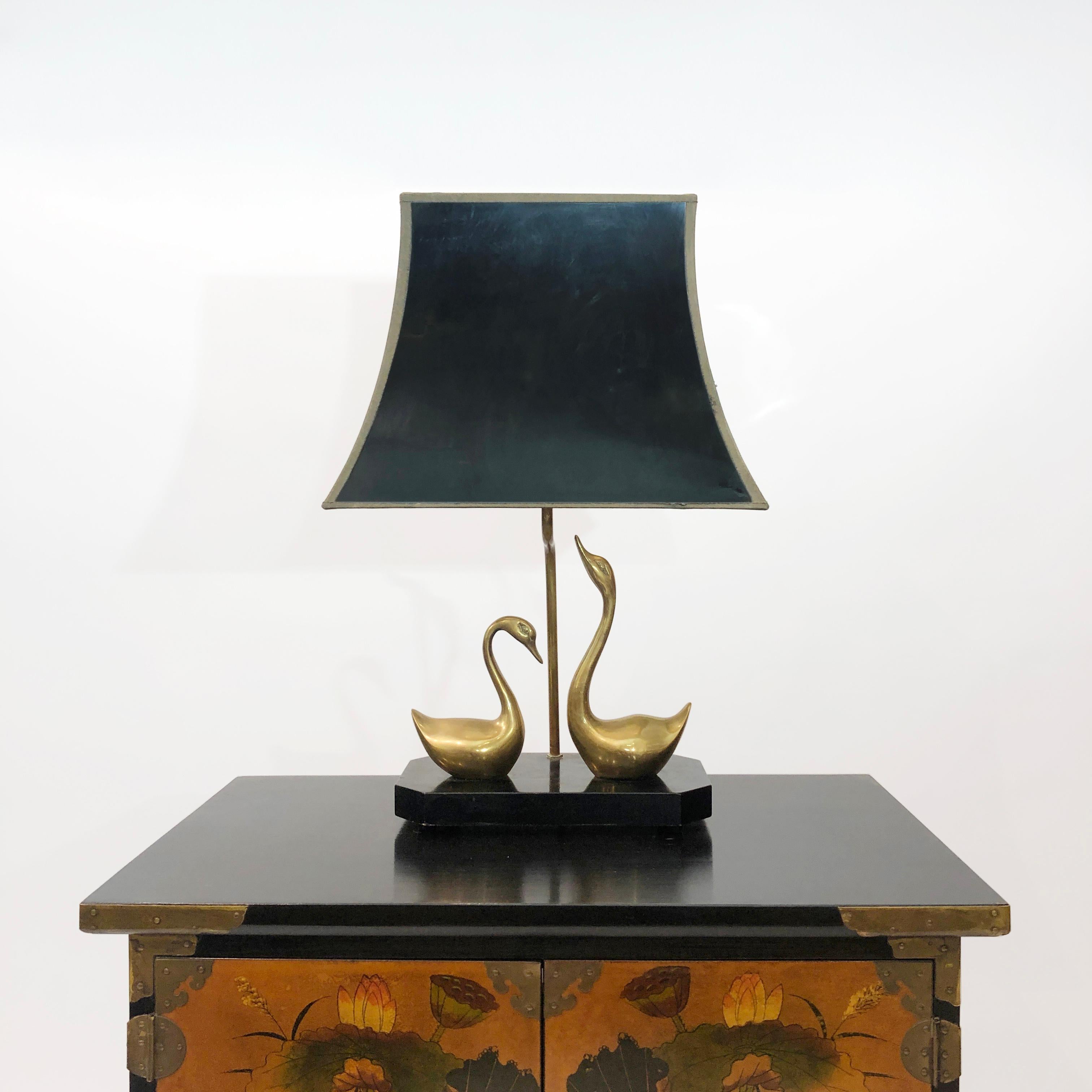 A table lamp from the legendary French interior design firm Maison Jansen, depicting two courting swans. Each swan is elegantly produced from patinated brass, with one slightly stretching its neck upwards. The organic curved lines of each bird sit