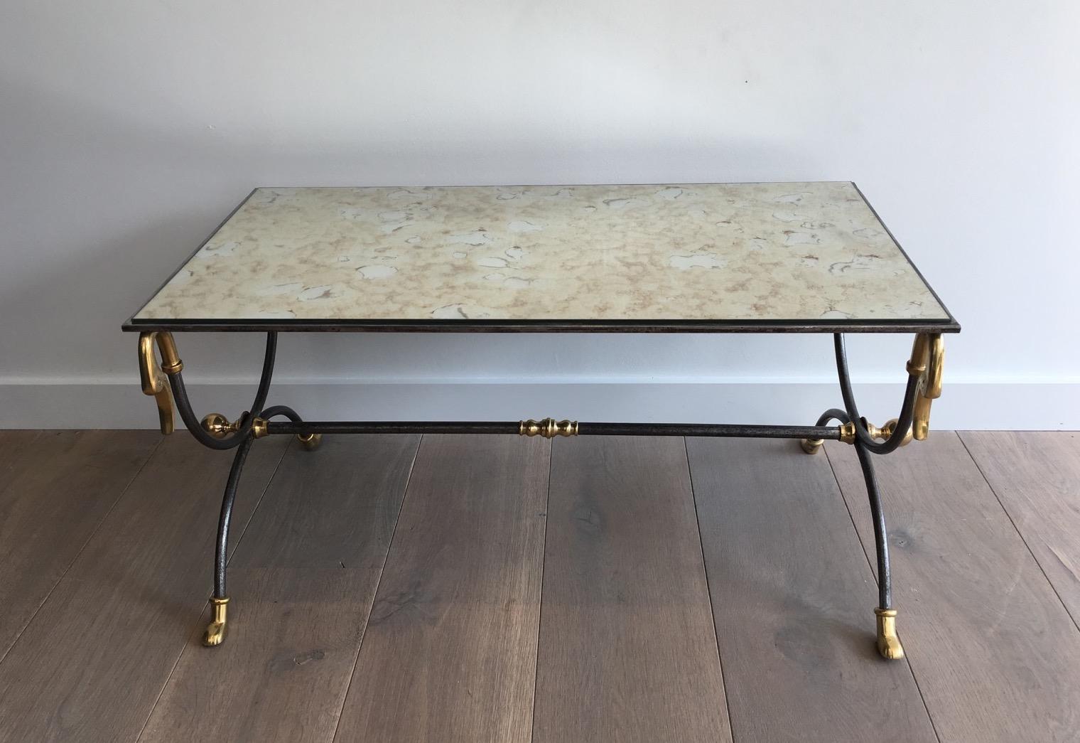 This very elegant coffee table is made of a neoclassical brushed steel base with brass swan heads and feet. It has a faux-antiques mirror. This is a French work attributed to Maison Jansen, circa 1970.