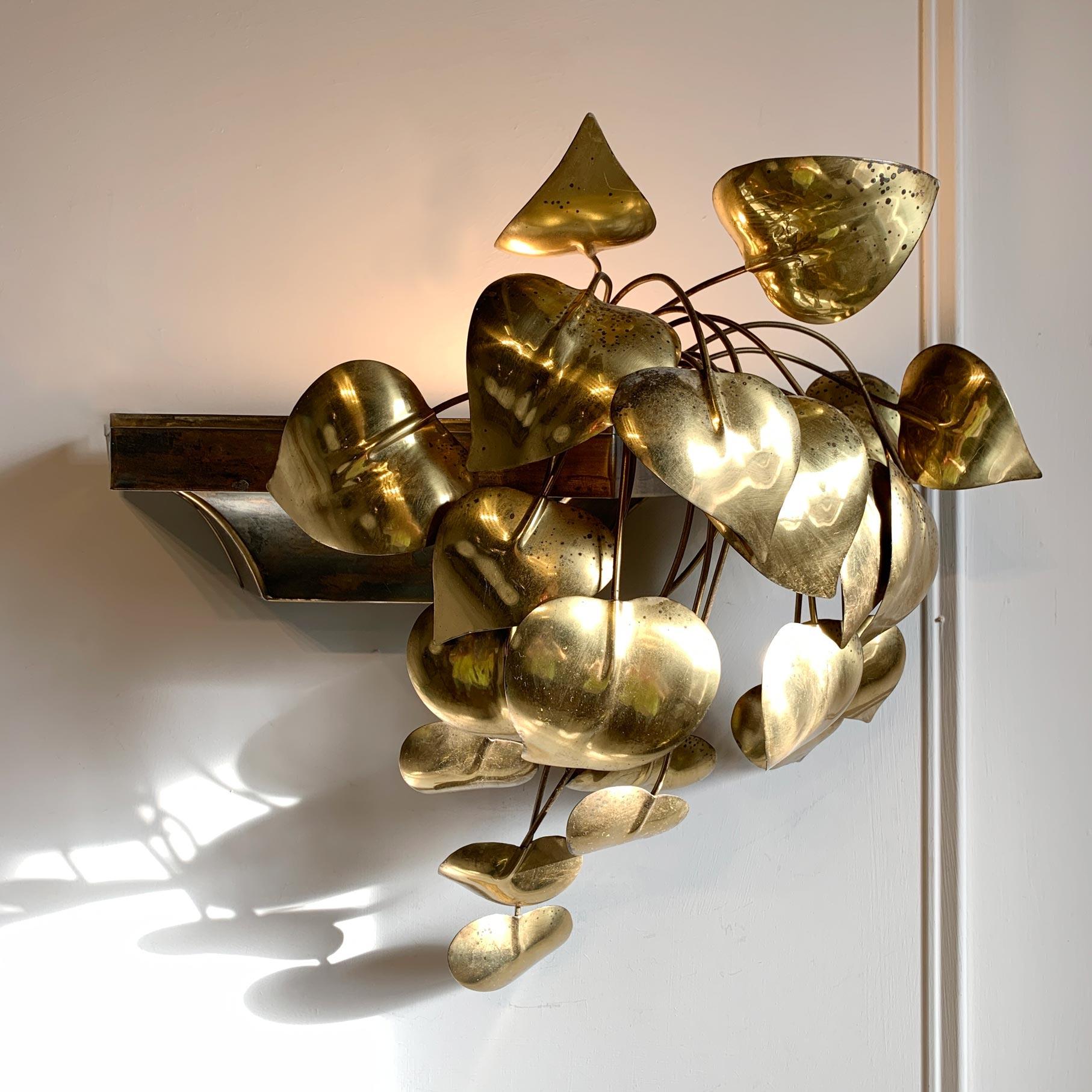 The cascading leaves wall light, attributed to Maison Jansen. This mesmerizing wall light features cascading foliage, hand worked in brass, the leaves tumble out of and down the outside of the vase, this houses the single e14 lamp holder, which