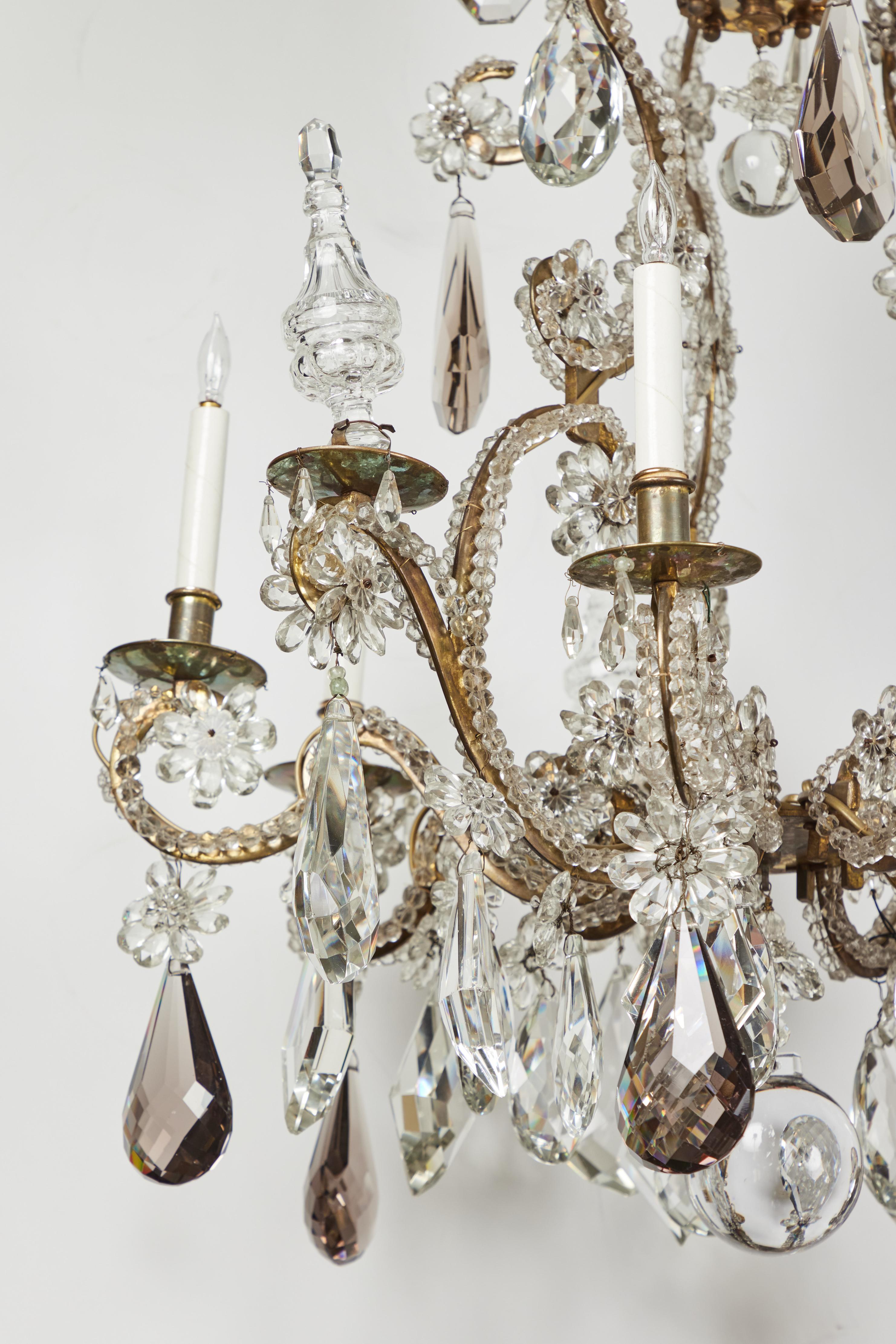 Elegant 6 light chandelier by renowned French maker Maison Jansen. This chandelier features crystal and smokey quartz teardrops, crystal poniards, crystal flowers and beading over the beautifully shaped scrolled gilded metal frame.
 