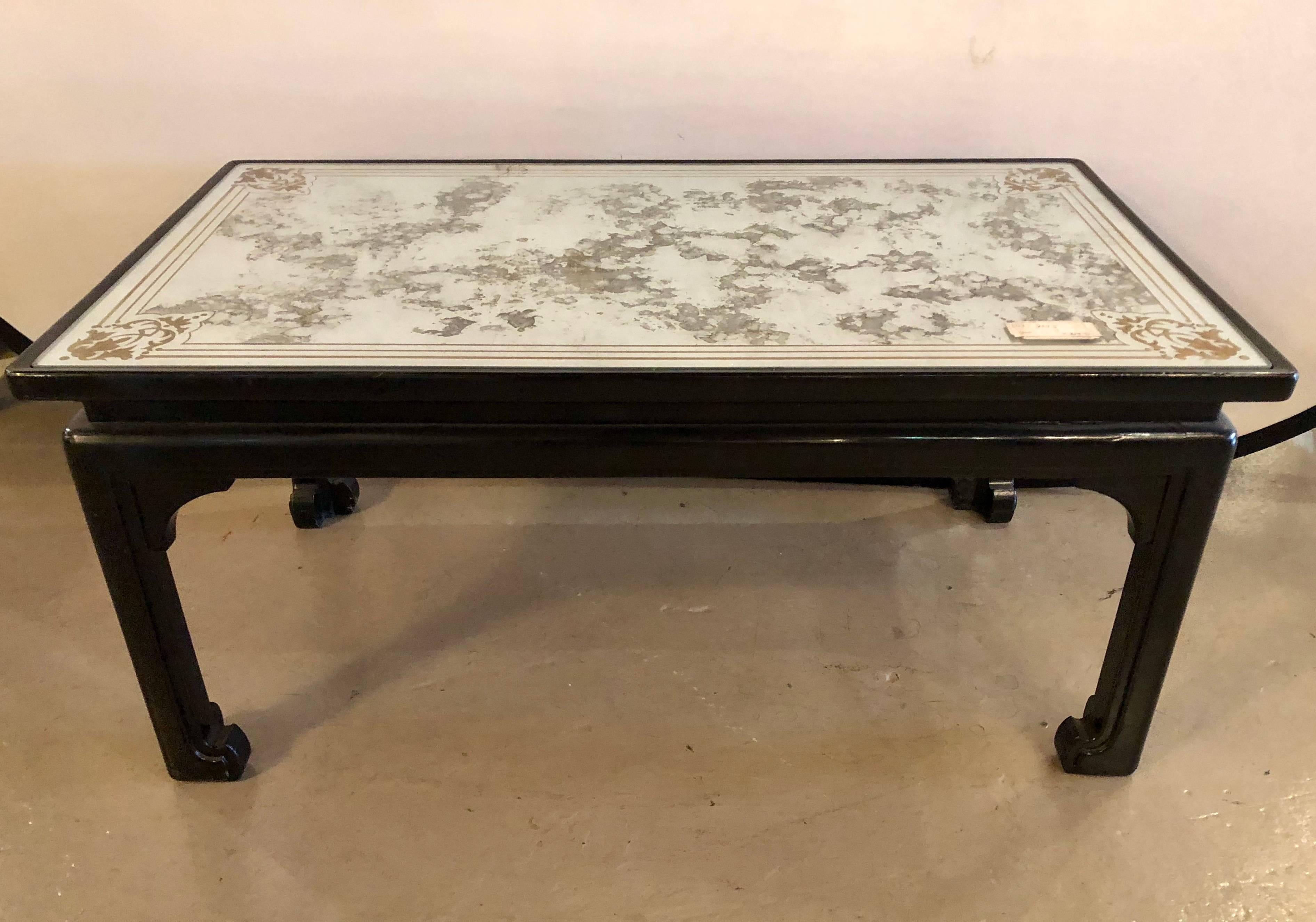 Finely ebonized coffee or cocktail table, in the chinoiserie manner. The rectangular mirrored top having a finely decorated églomisé design inset inspired by Maison Jansen on an Asian inspired base. This table showcases the Hollywood Regency era at