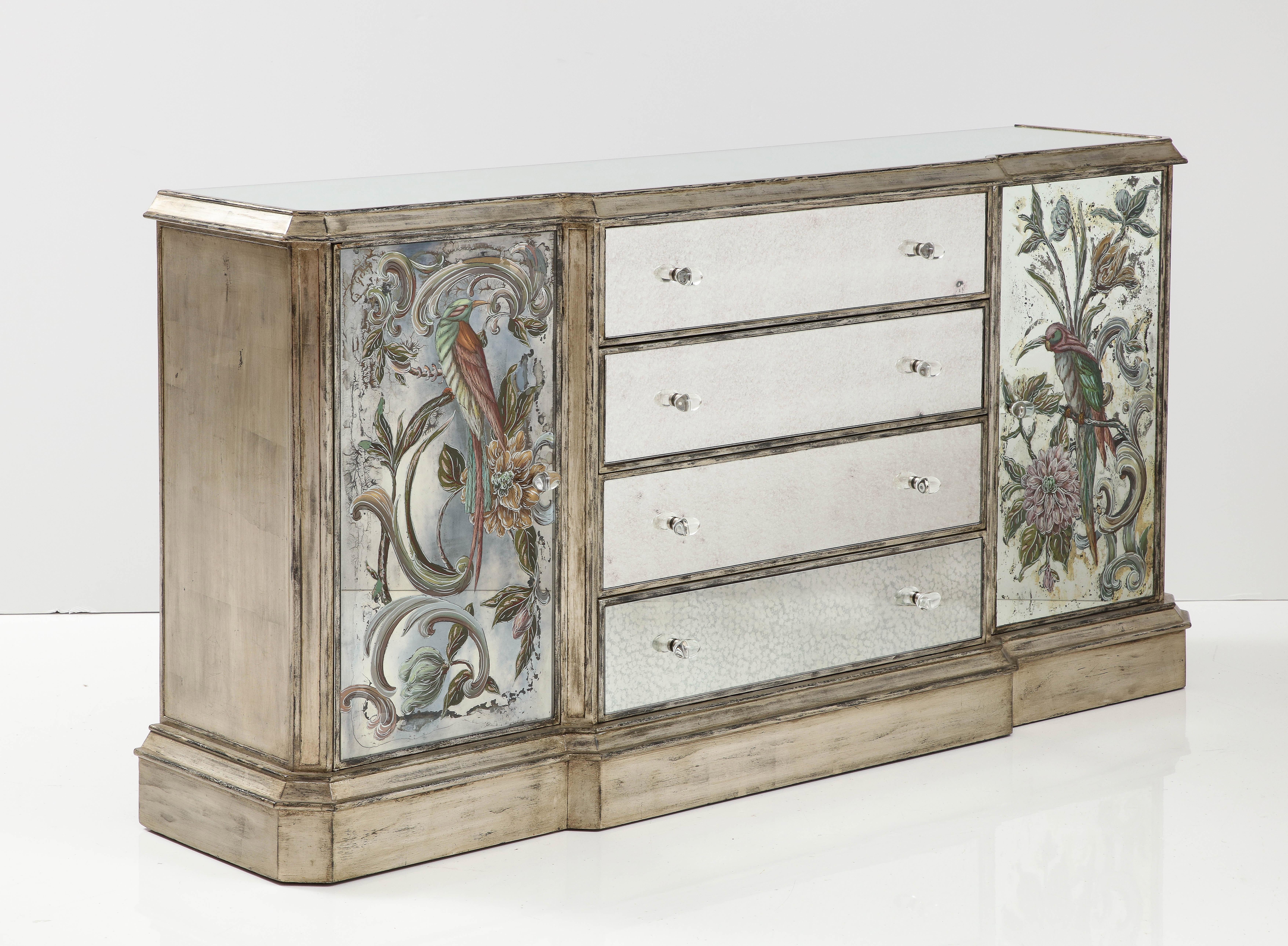 Chinoiserie inspired hand painted eglomise mirror paneled credenza featuring fanciful exotic birds. Credenza features 4 spacious mirrored front central drawers and 2 side compartments all with glass oval pulls. Case features an aged hand silver