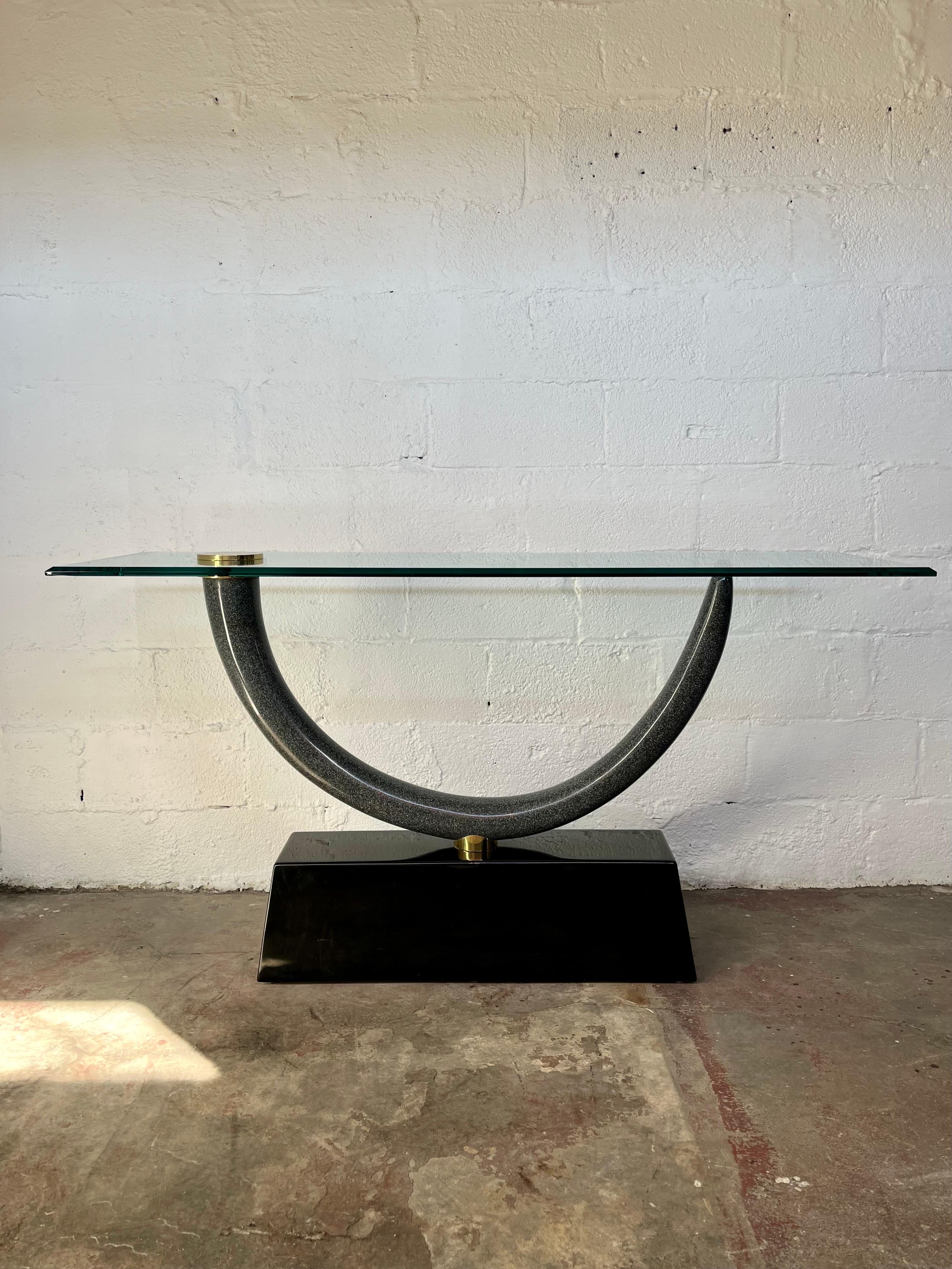 This is an iconic Maison Jansen Tusk form console table with a gorgeous resin tusk and glass top with a brass and a black ebonized base. The table is in very good condition but will show signs of use such as minor surface scratches on the top and