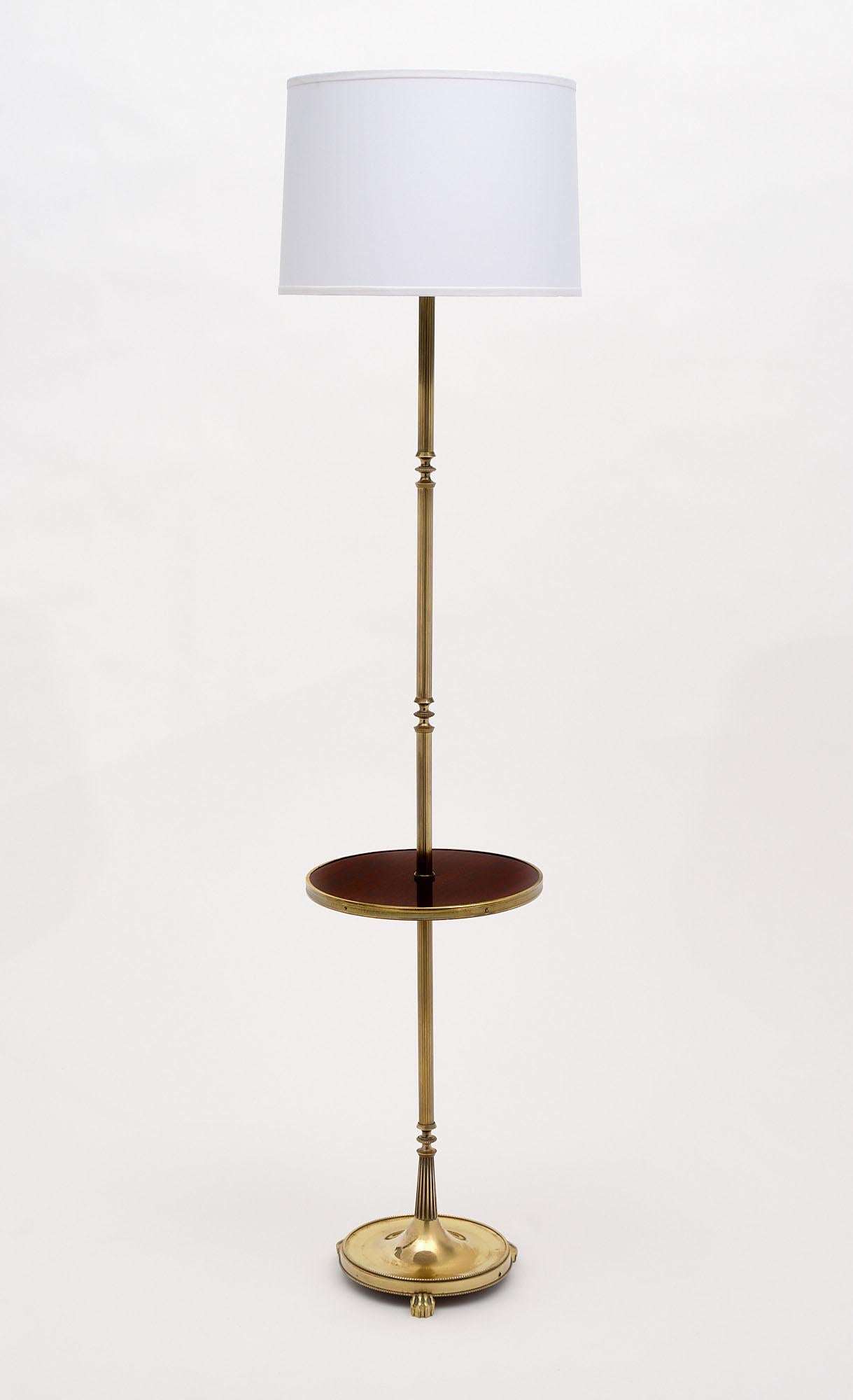 Floor lamp from France by Maison Jansen. This piece is made of polished brass with a tripod base and a spheric rosewood shelf in the center. The fixture comes with a new white silk-blend shade. It has been newly sired to US standards.