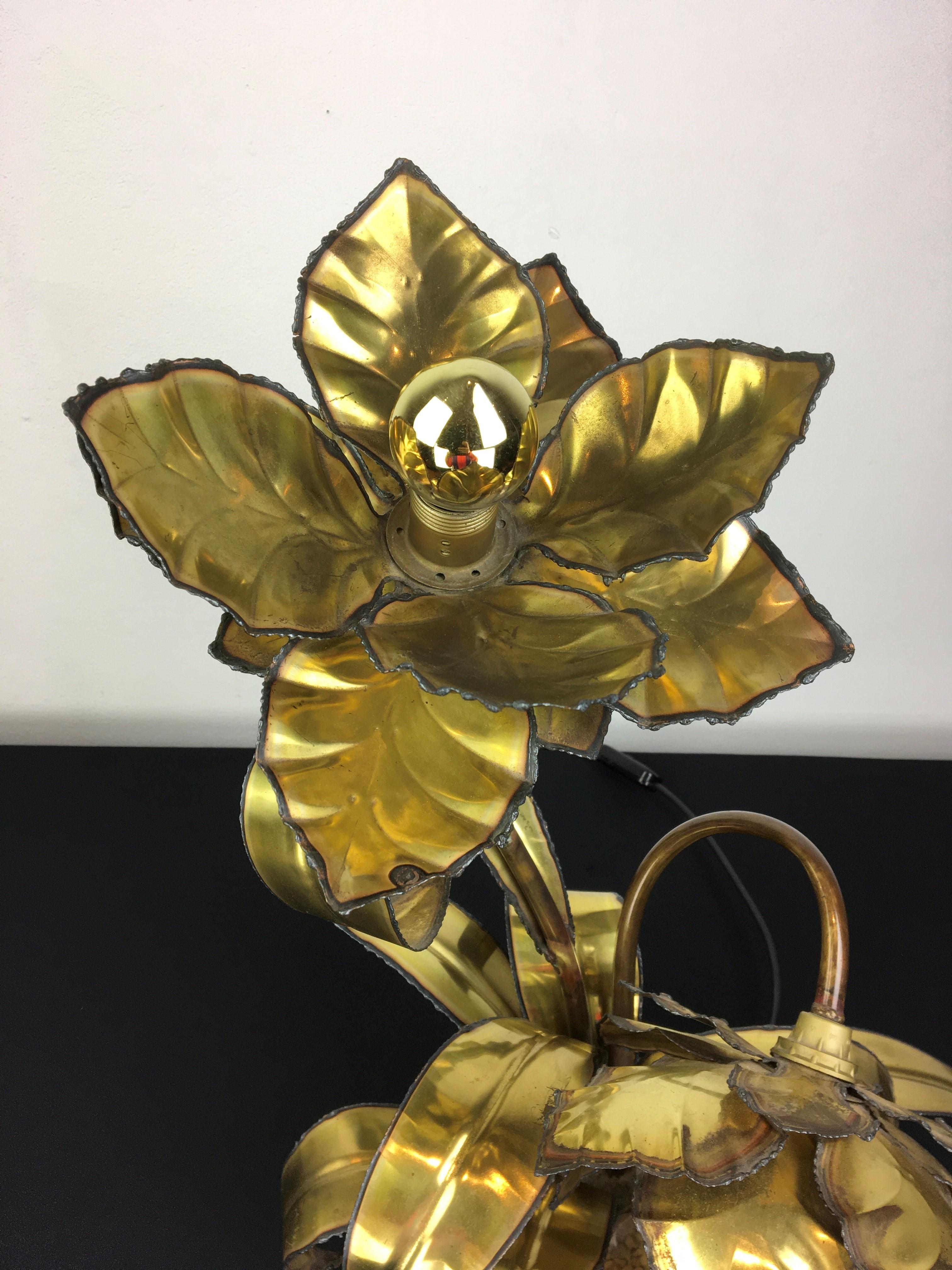 Maison Jansen flower table lamp. 
This 1970s French cut brass table light has 2 flowers , one flower up and one flower down. The flower lamp - flower plant has a round base filled with white little stones.
It's very stylish and timeless lighting