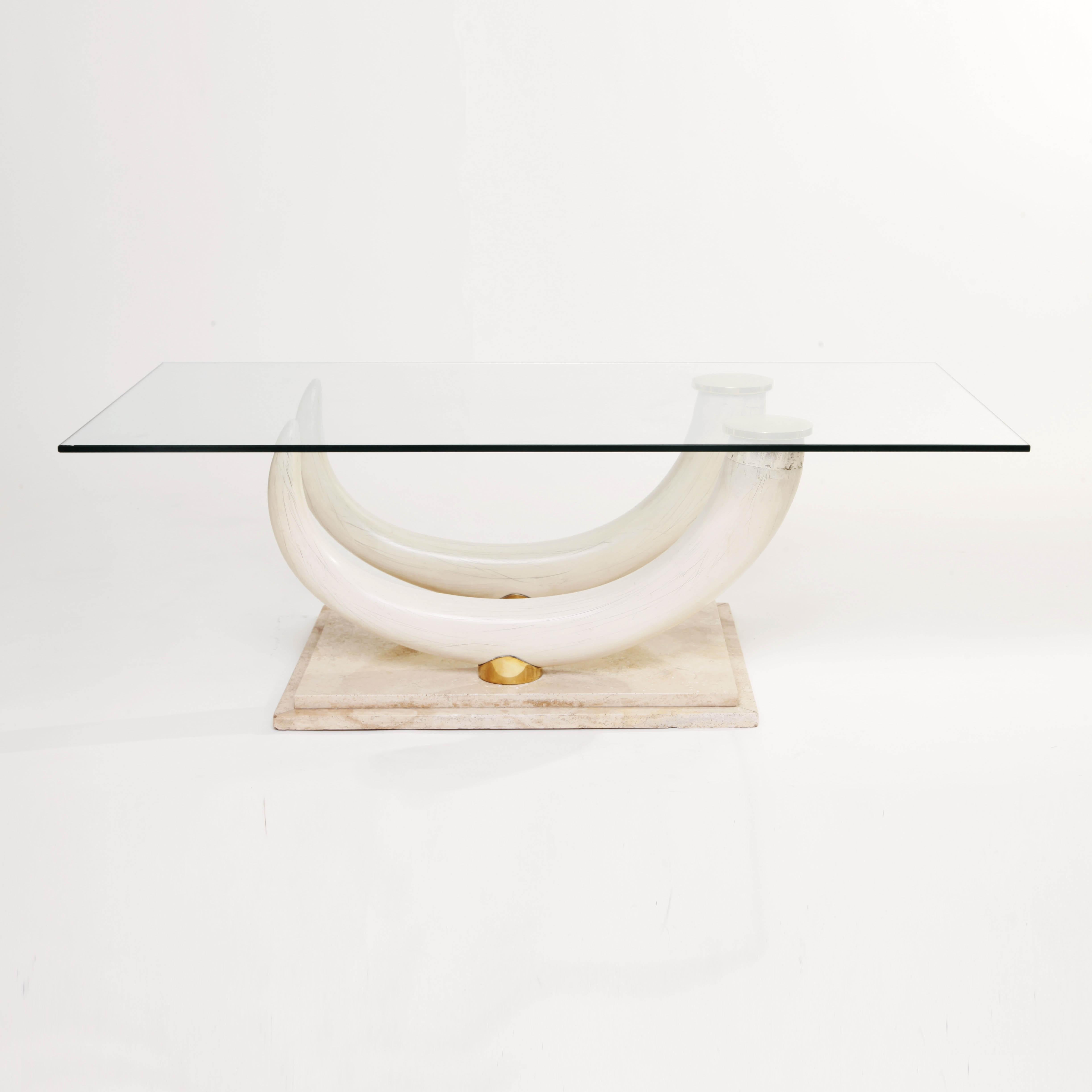 A unique coffee table designed by Maison Jansen and manufactured by Ralph Pucci collections, Italy. Travertine stepped base with faux elephant tusks and brass joins. Clear glass top. Signed on the brass fixings.
     