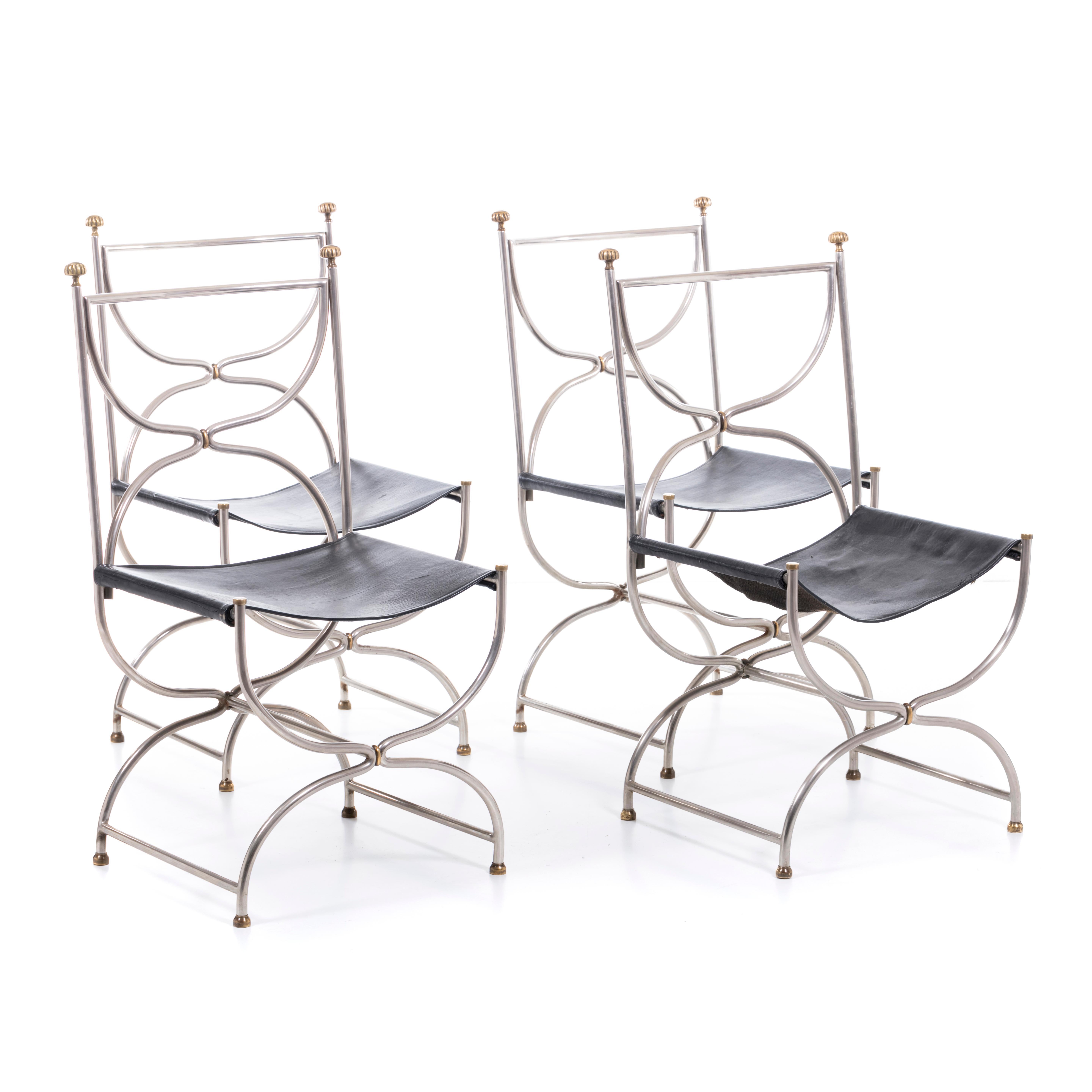 A Set of 4 elegant French 1960's Curule Savonarola chairs by Jansen, Made of steel and brass with original black leather seat showing beautiful patina, The minimal scultural structure contrasting nicely with the organic leather seat.