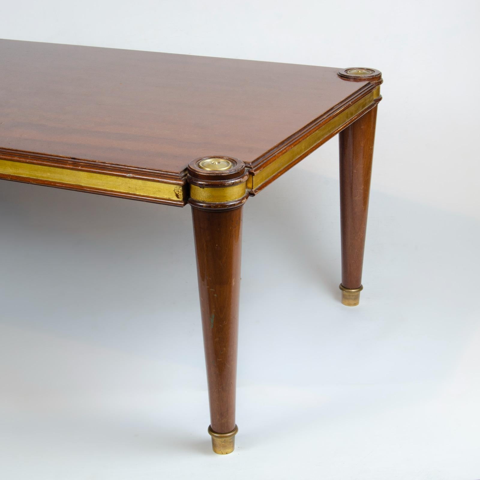 This French Art Deco coffee table is from Maison Jansen. The 1940s table is constructed of stained oak with gold leaf collars above the leg. The table bed has a decorative 1940s design and feet are brass tipped.
