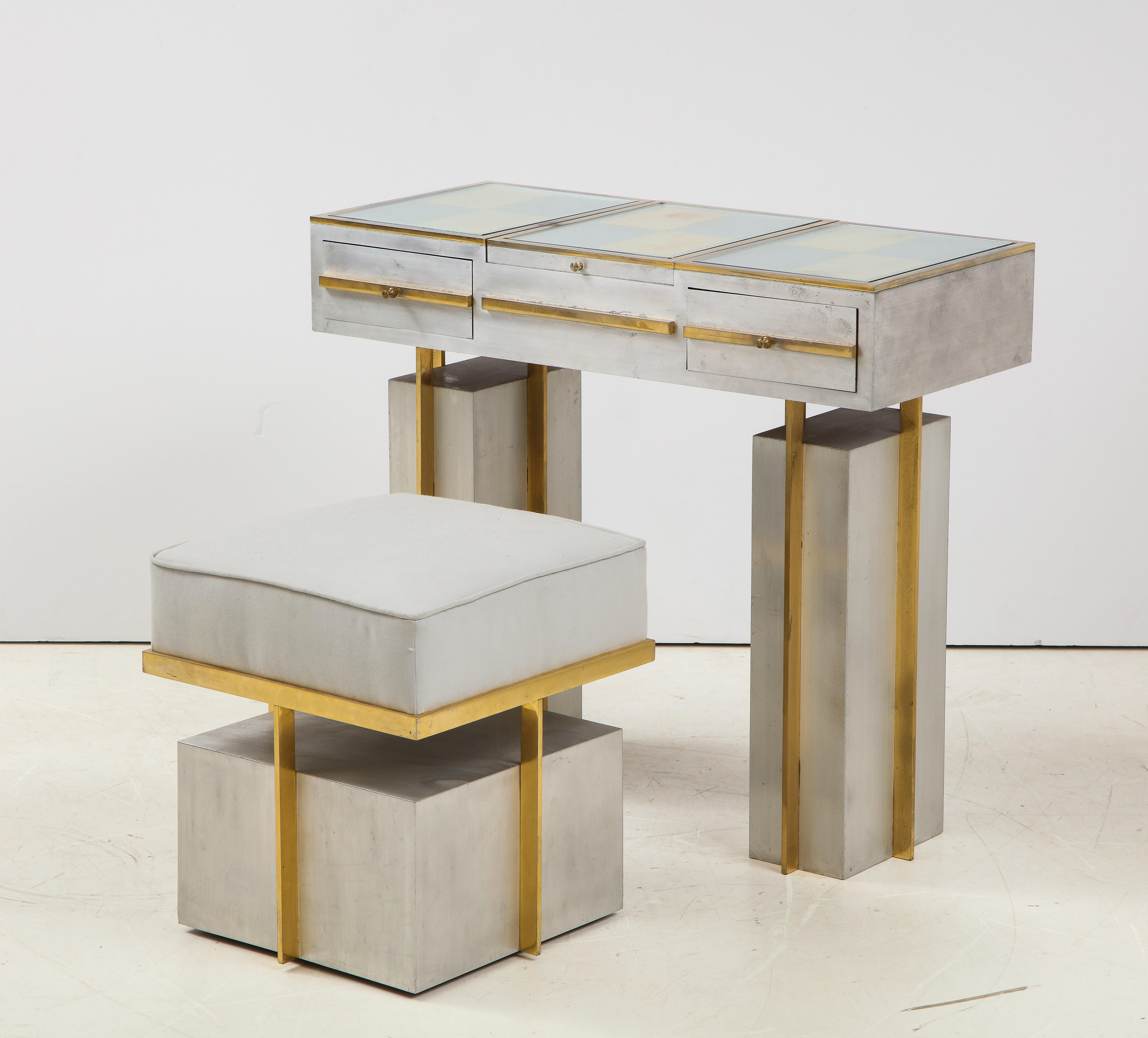A stunning Geometric modernist style vanity and matching chair by Maison Jansen. This gem is in steel and brass brings a streamline deco look to a seventies jewel. A flip top reveals a concealed mirror and compartment. The stool fits neatly under it