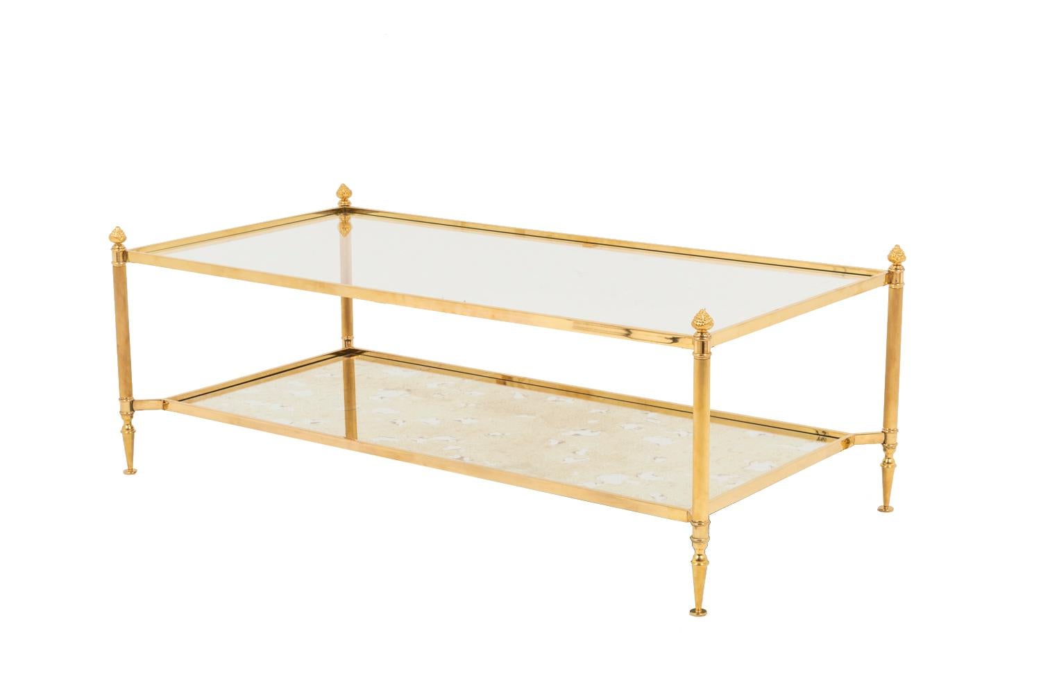 Maison Jansen, in the style of.

Rectangular coffee table in gilt brass, glass and oxidized mirror standing on four fluted circular legs, with rings,ending in cones and topped by pine cones. Inferior tray in oxidized mirror fixed on legs by four