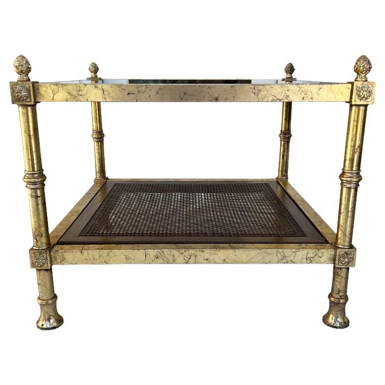 A fabulous pair of Hollywood Regency or Neoclassical metal, cane, and glass Maison Jansen side tables. Each table is square with a gilt metal gold body. The tops have the original smokey glass tops that are inset. The bottom shelf is created with a