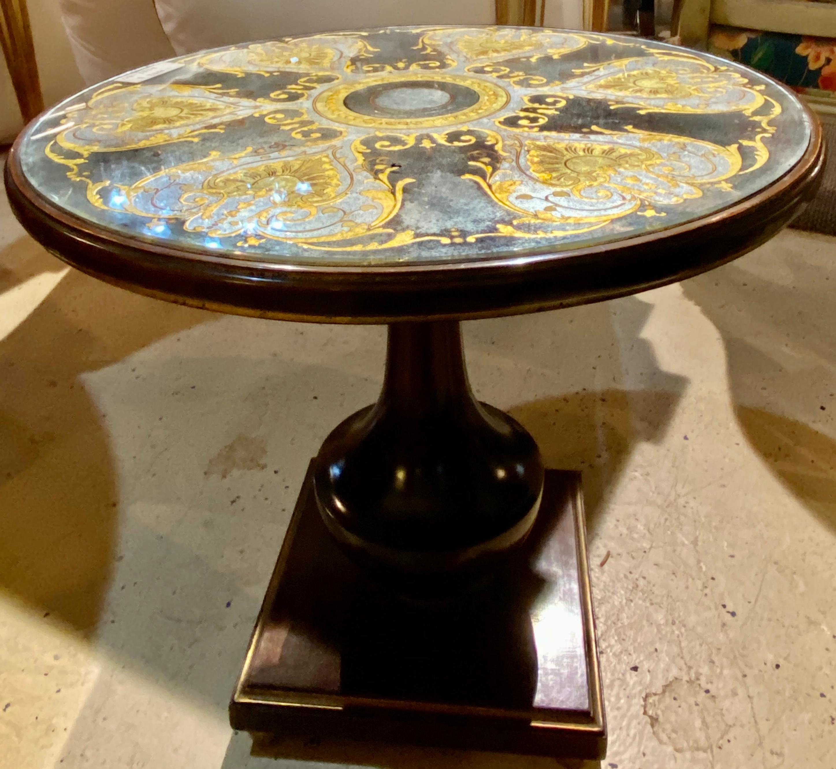 French Empire style mahogany and parcel-gilt gueridon occasional table, the circular top with verre Églomisé glass inset, atop a single pedestal supported by squared block base. By Maison Jansen.