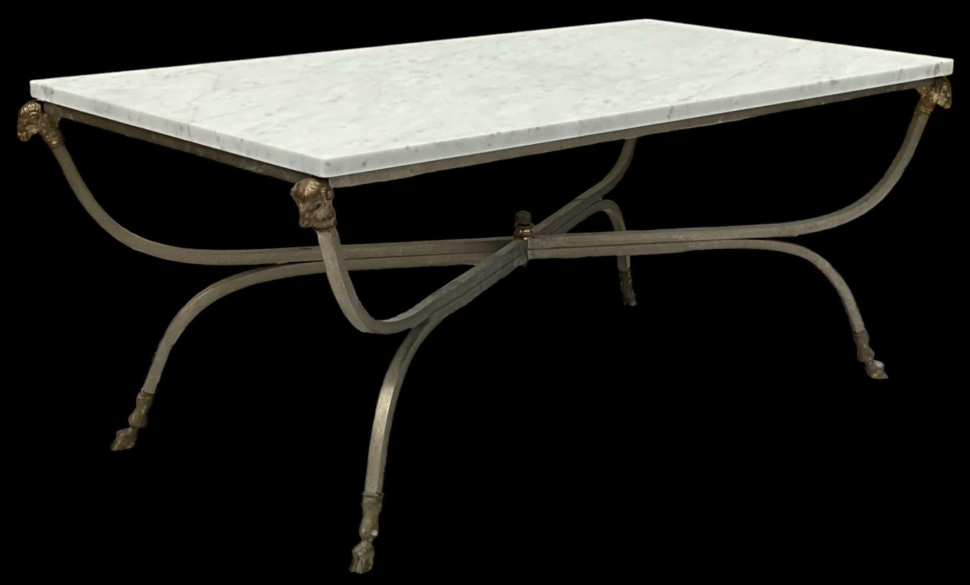 This is a 1970s Maison Jansen inspired marble top coffee table. It is Italian and marked under one hoof. The frame is steel with bronze ram’s head and hoof appointments. The white marble has a subtle grey veining. It is honed. It is in very good