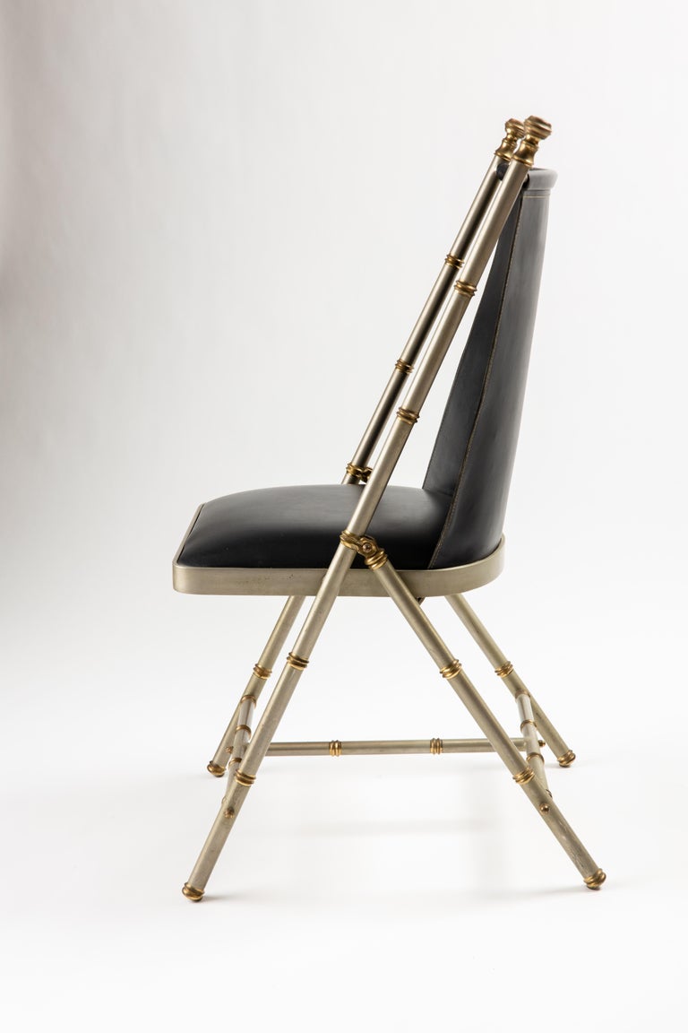 Maison Jansen steel and bronze campaign chair with leather back and upholstered seat. Bronze detailed side hinges are exquisitely crafted, along with finials, and rings around the gun metal finished steel sides and legs. 
Seat measures 17