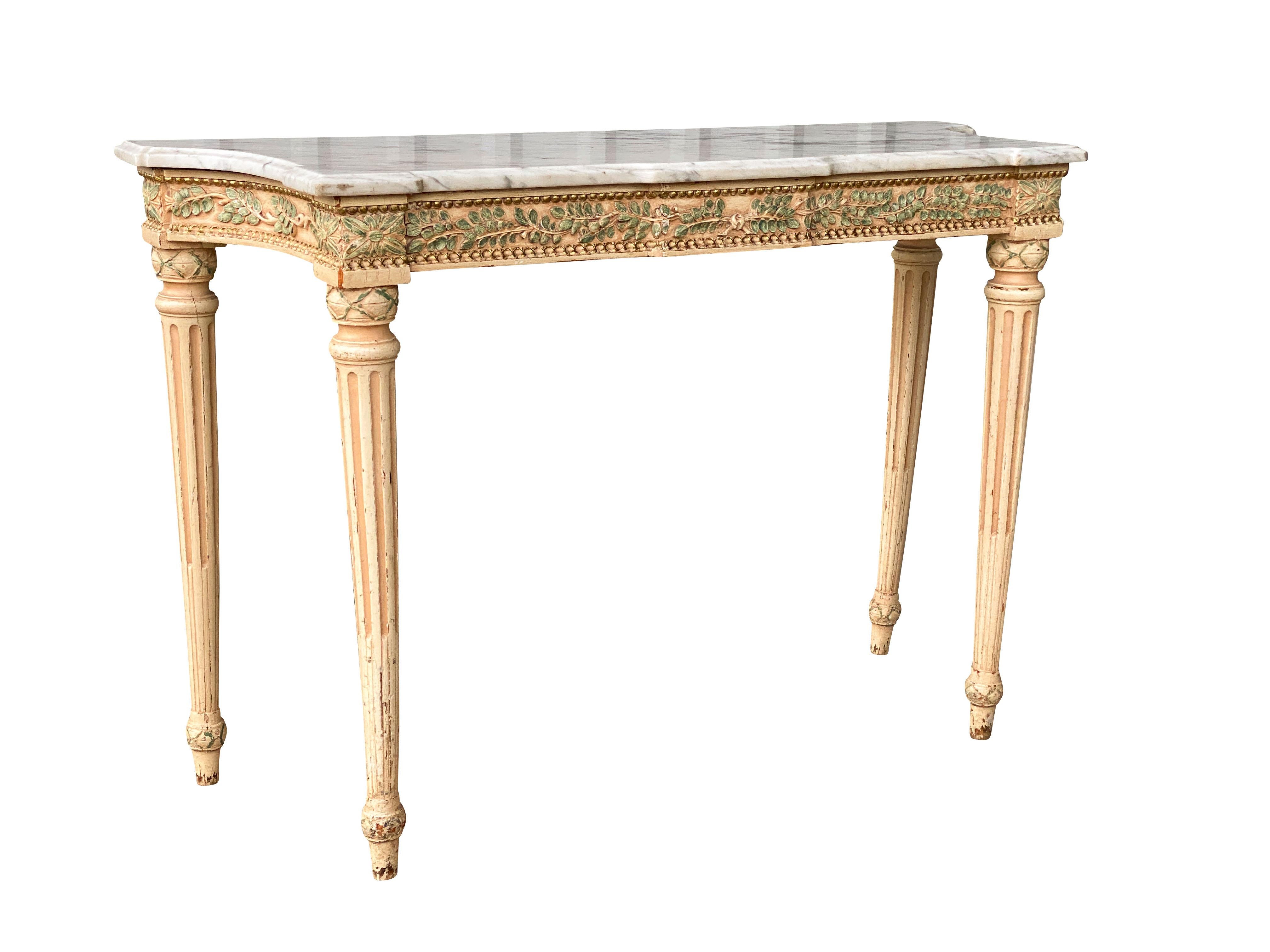 Shaped rectangular white and grey marble top over a conforming frieze carved with green painted laurel leaves and raised on circular tapered stop fluted legs. Provenance; Waldorf Towers NYC. Original 1931 furnishing. See a very similar table in