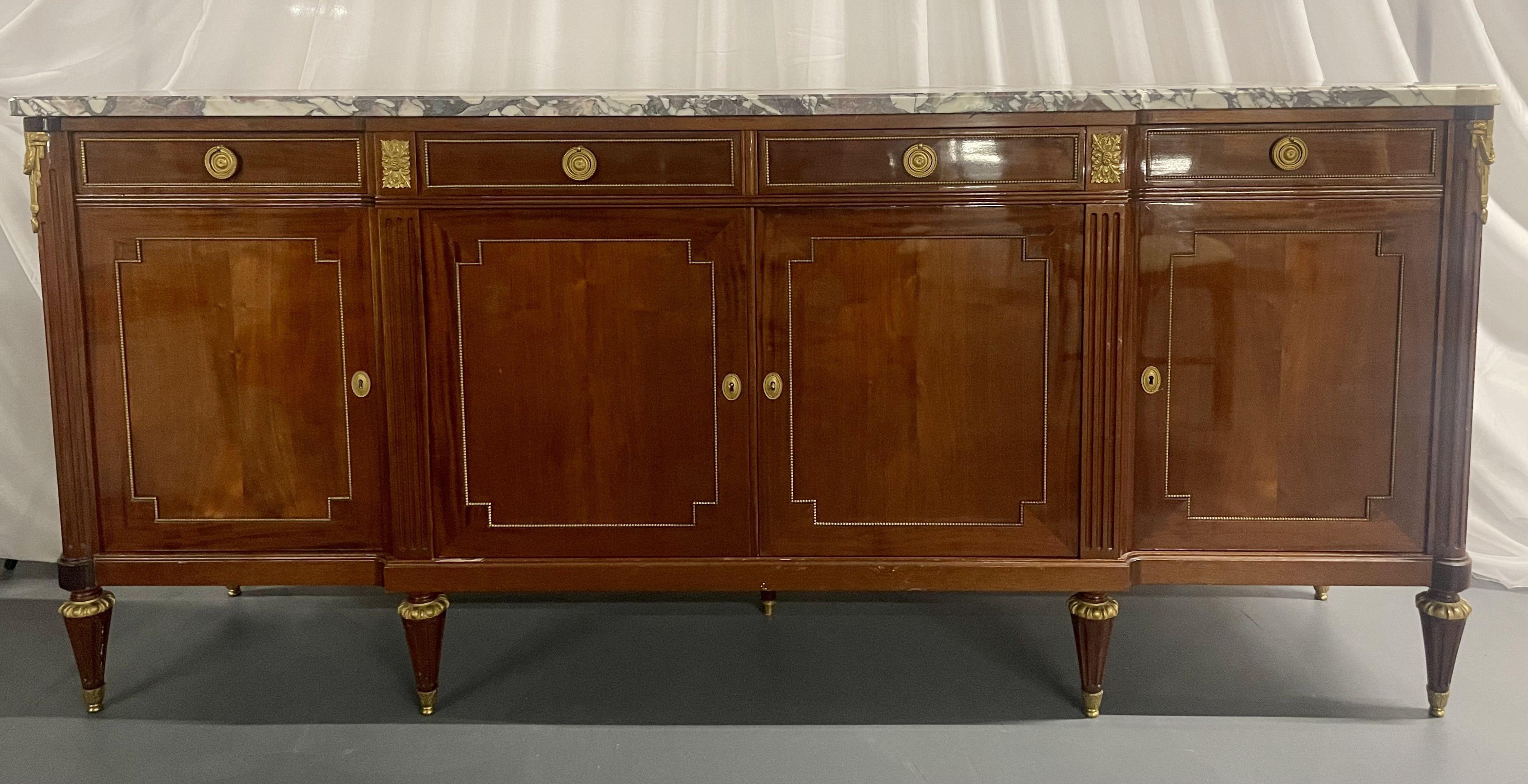 A French Louis XVI Style Sideboard in Maison Jansen Fashion. This stunning bronze mounted credenza, sideboard sports a fine Breche marble top and bronze trim throughout. The case having bronze mounted legs supporting four doors leading to fitted