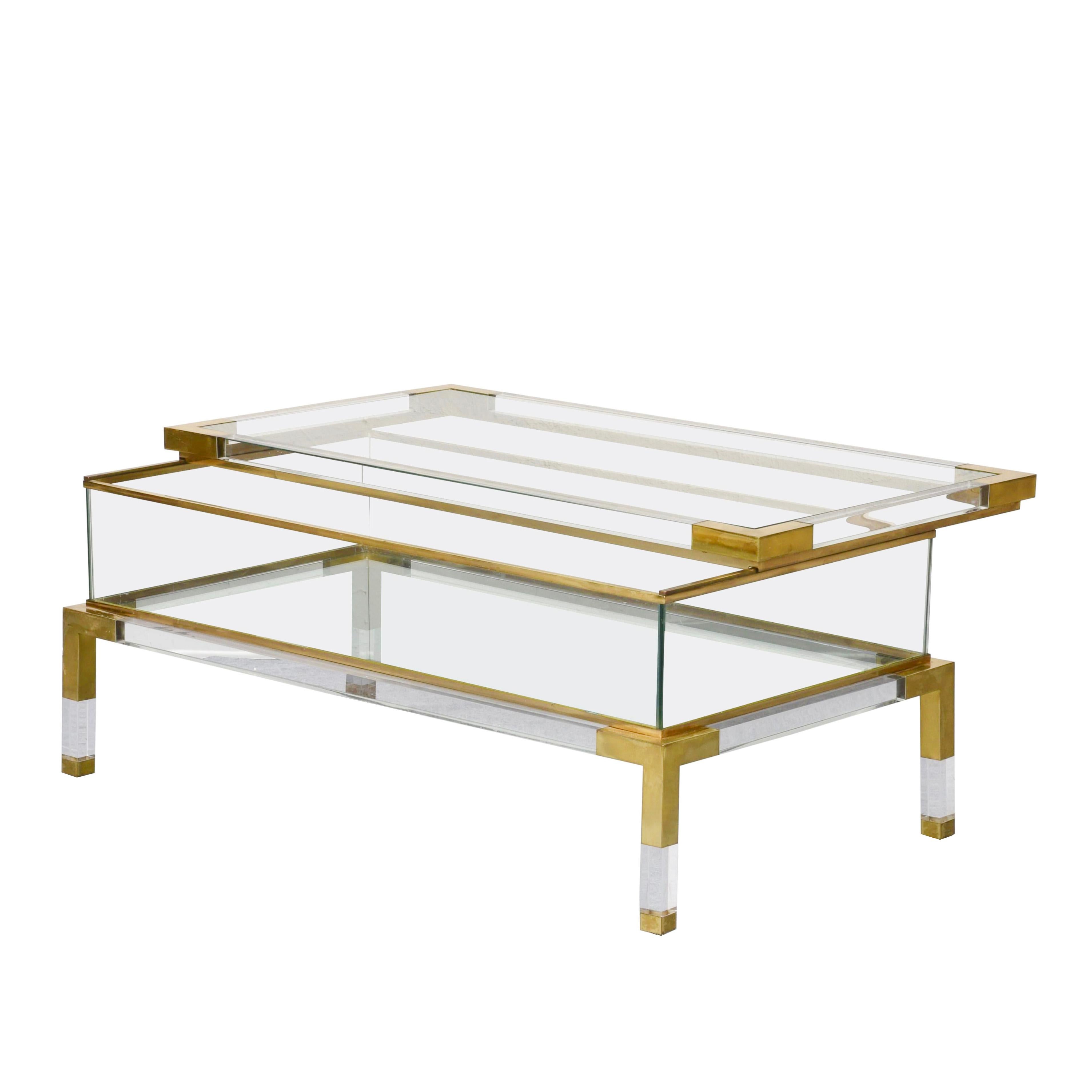 Beautiful mid-century coffee table in brass and lucite with sliding top shelf. This fantastic piece was designed by Maison Jansen in France during the 1970s.

This fantastic item is in good condition and has a double glazed top. The top can slide