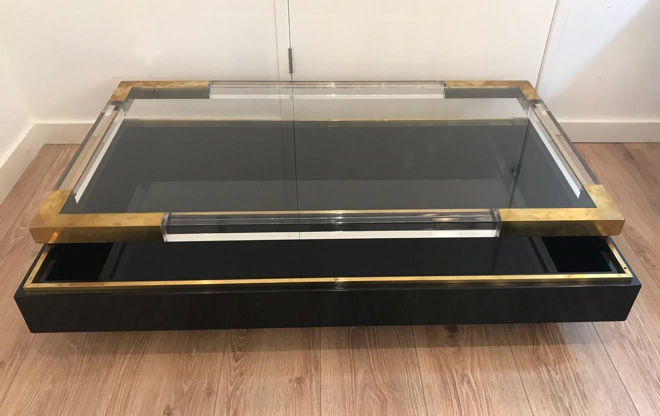 Maison Jansen coffee table, Lucite and brass sliding glass top concealing an interior display case/vitrine, ideal for presenting books and or decorative items.