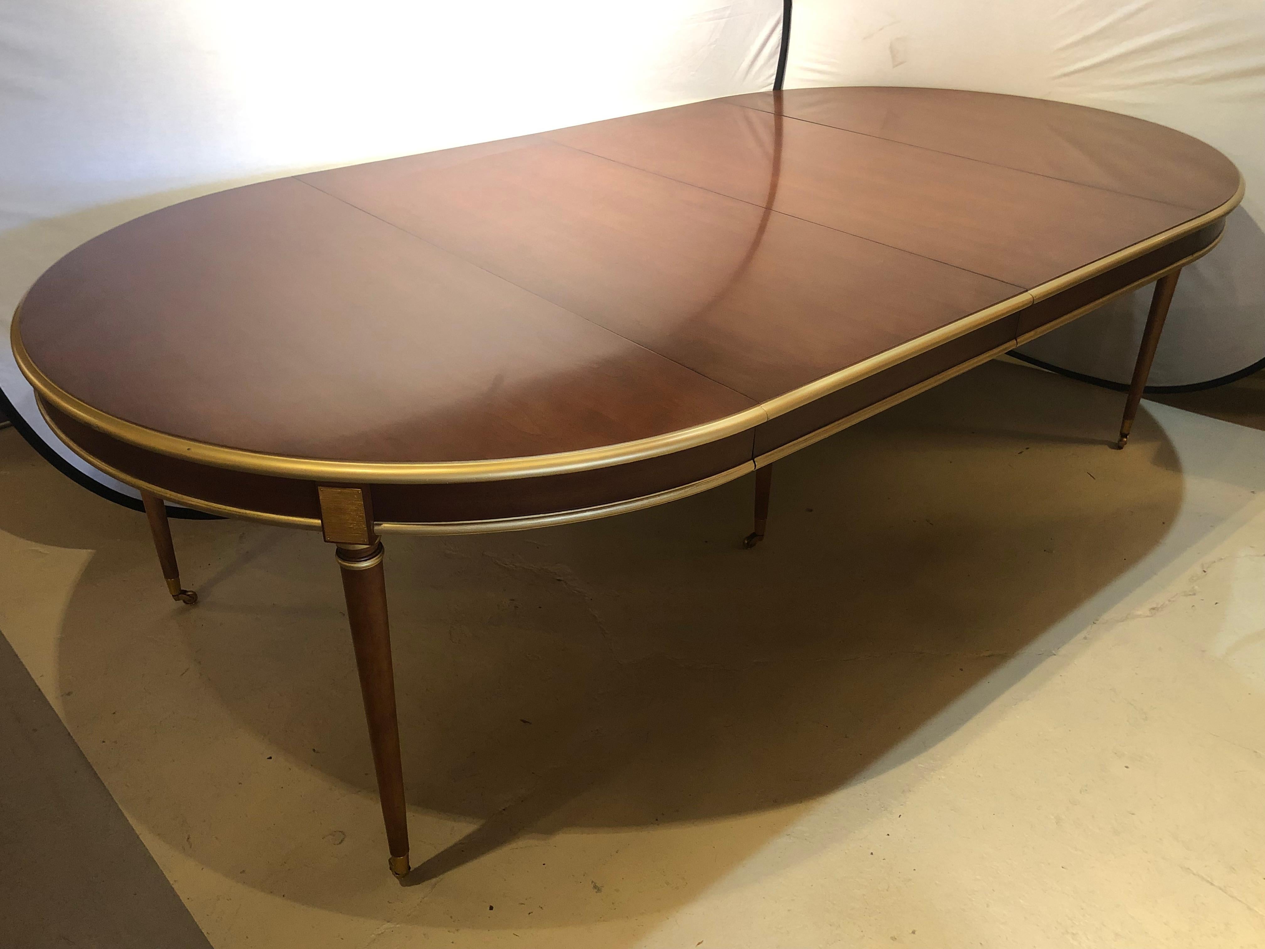 A large and impressive dining table that is circular in fashion and open to a large oval of 126 inches. This Maison Jansen Dining table has Louis XVI Fashion with its sleek and simple lines making it versatile enough to sit in any Hollywood regency
