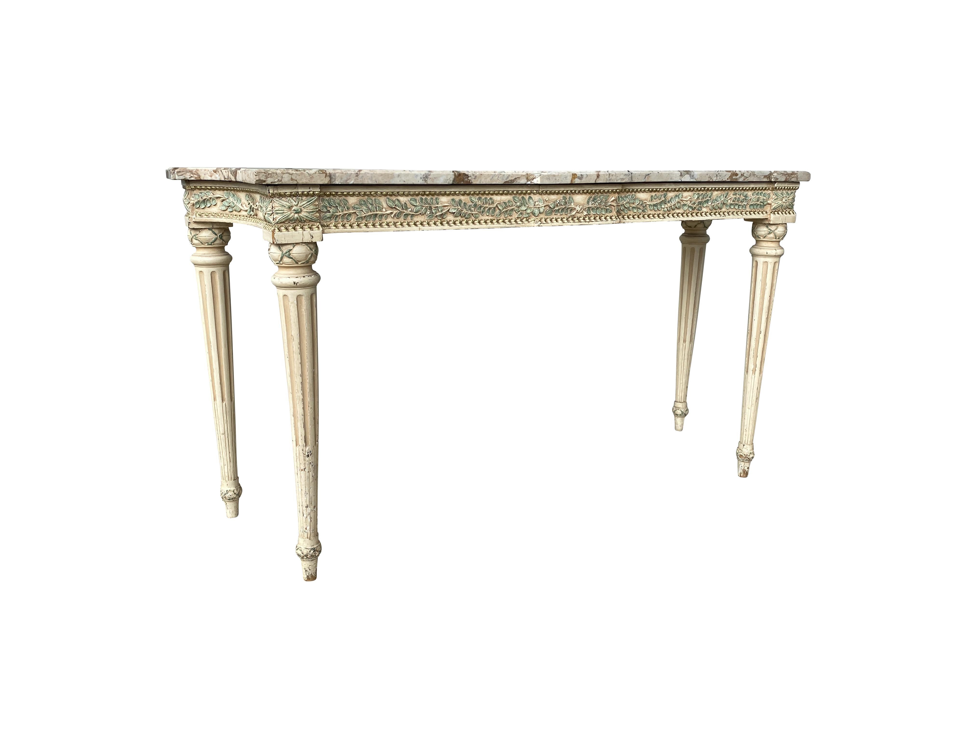 Rectangular top with curved ends over a conforming frieze carved with green painted laurel leaves, raised on circular tapered stop fluted legs. This table was originally installed in the Waldorf Towers in New York in 1930. Metal label on back.