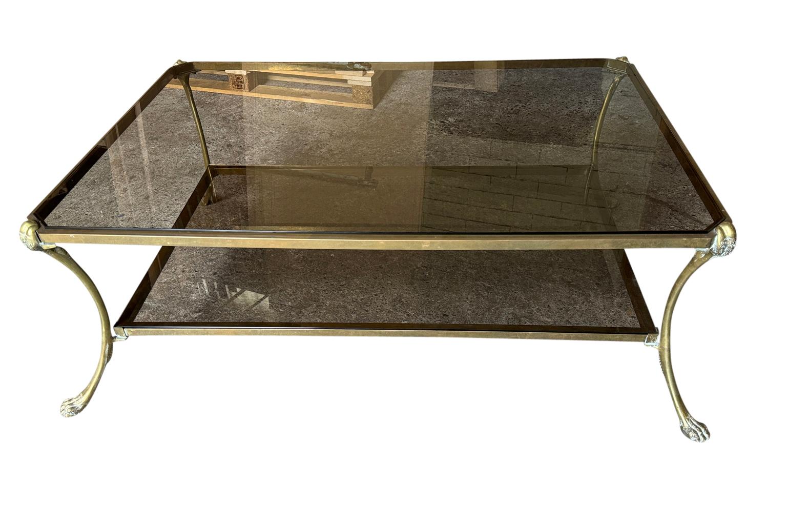 Une très élégante table à cocktail - table basse de la Maison Jansen du milieu du 20e siècle. Merveilleusement construit en bronze et en verre. Veuillez noter que le verre est légèrement fumé - il n'est pas aussi foncé que sur les photos