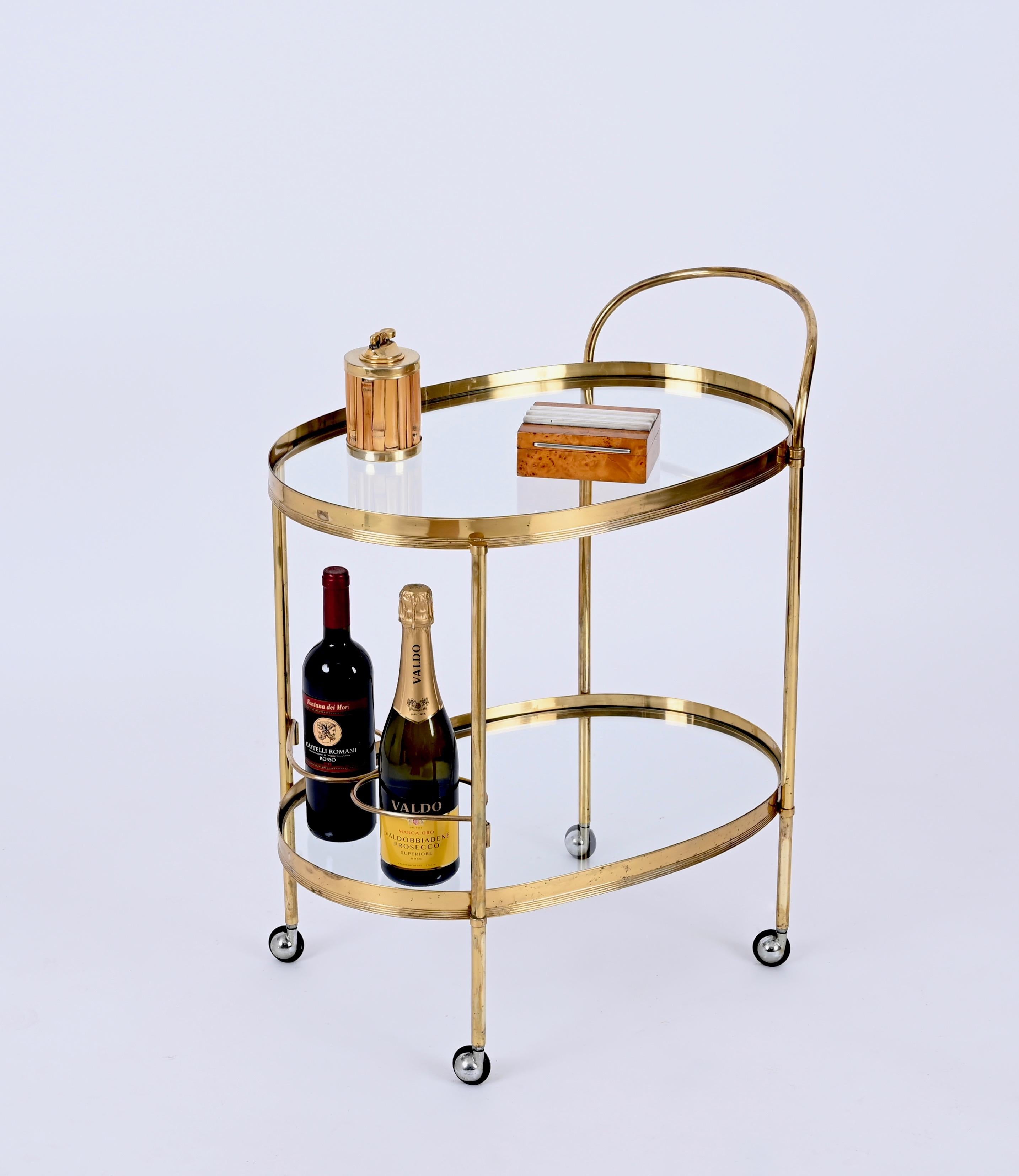 Magnificent mid-century brass and crystal glass bar trolley with bottle holder. This serving trolley was produced by the Maison Jansen in France during the 1970s.

The piece has tow crystalglass shelves, one on the top and one on the bottom, and