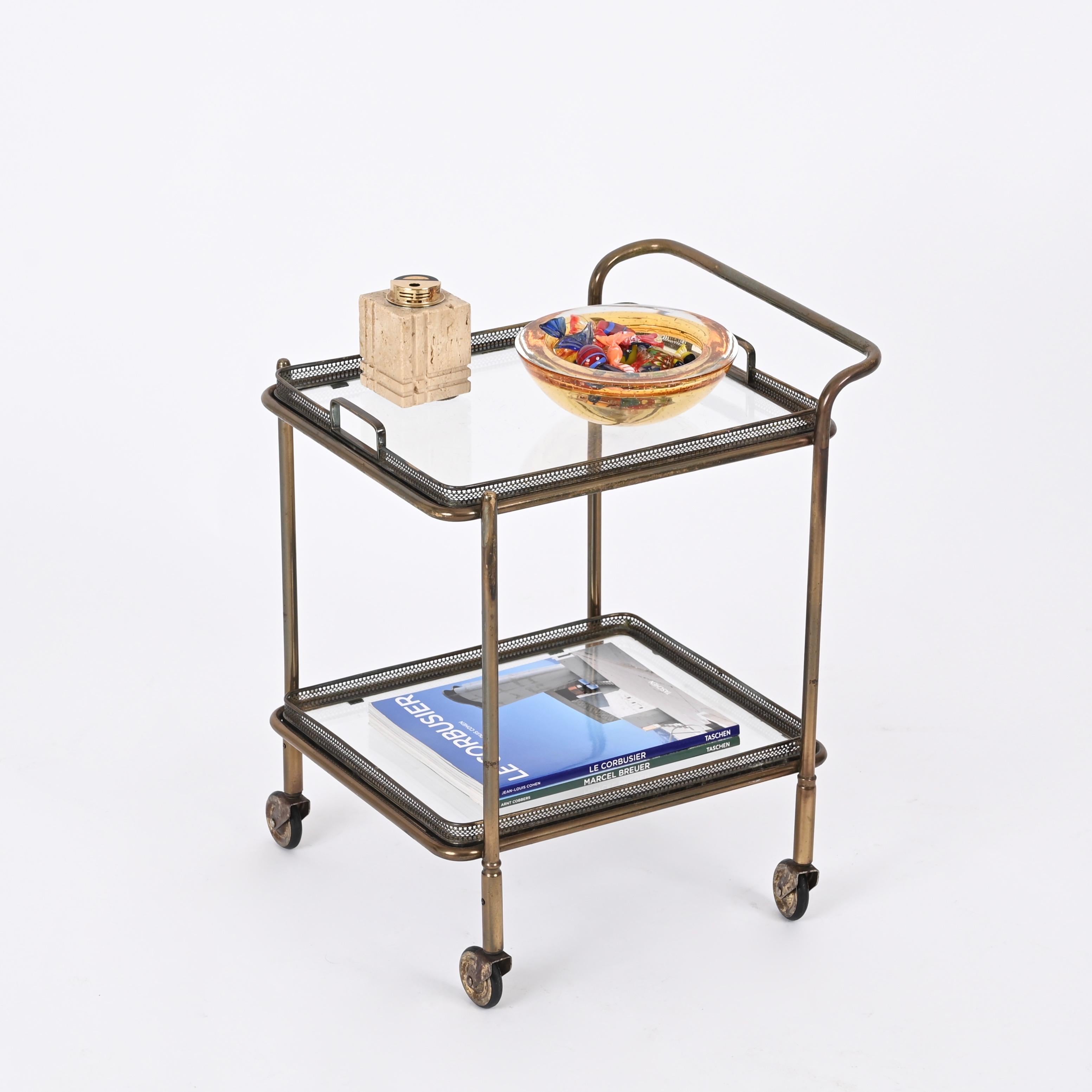Fantastic Mid-Century serving bar cart in solid brass and crystal glas. Maison Jansen produced this cosy serving trolley in France during the 1950s .

This lovely object is unique thanks to its small dimensions and perfect proportions. It has two