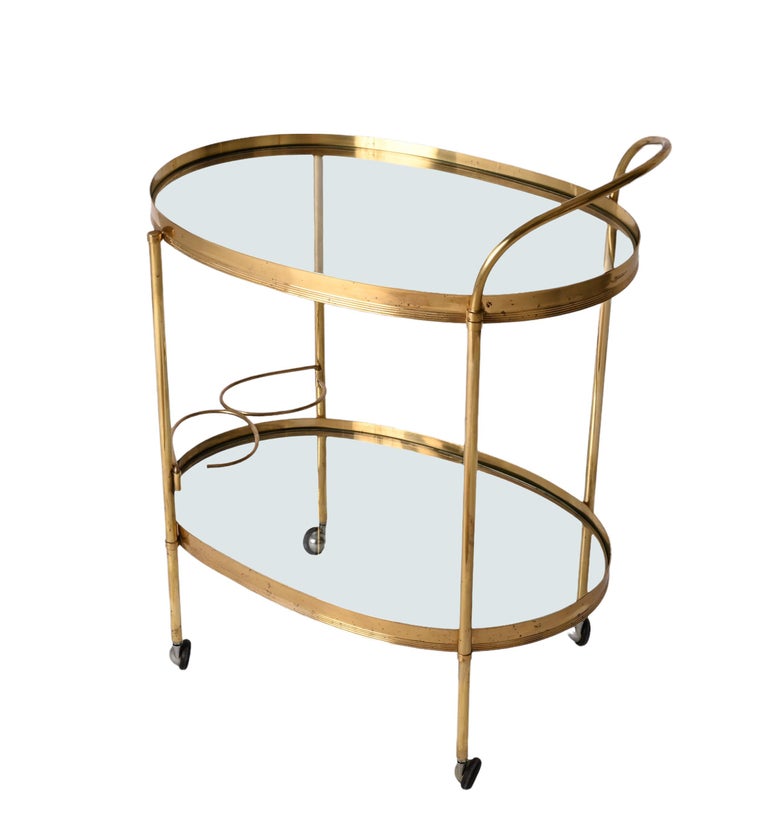 Magnificent mid-century brass and crystal glass bar trolley with bottle holder. This serving trolley was produced by the Maison Jansen in France during the 1970s.

The piece has tow crystalglass shelves, one on the top and one on the bottom, and