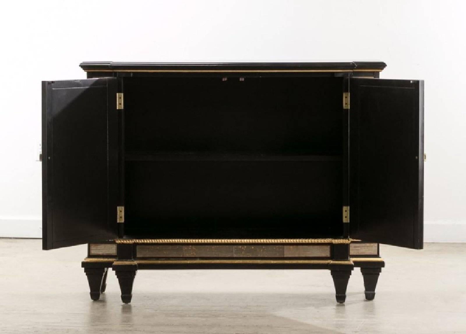A elegant two-door console cabinet with mirrored panels set in an ebonized wood body by Maison Jansen. Measures: Height 37.75