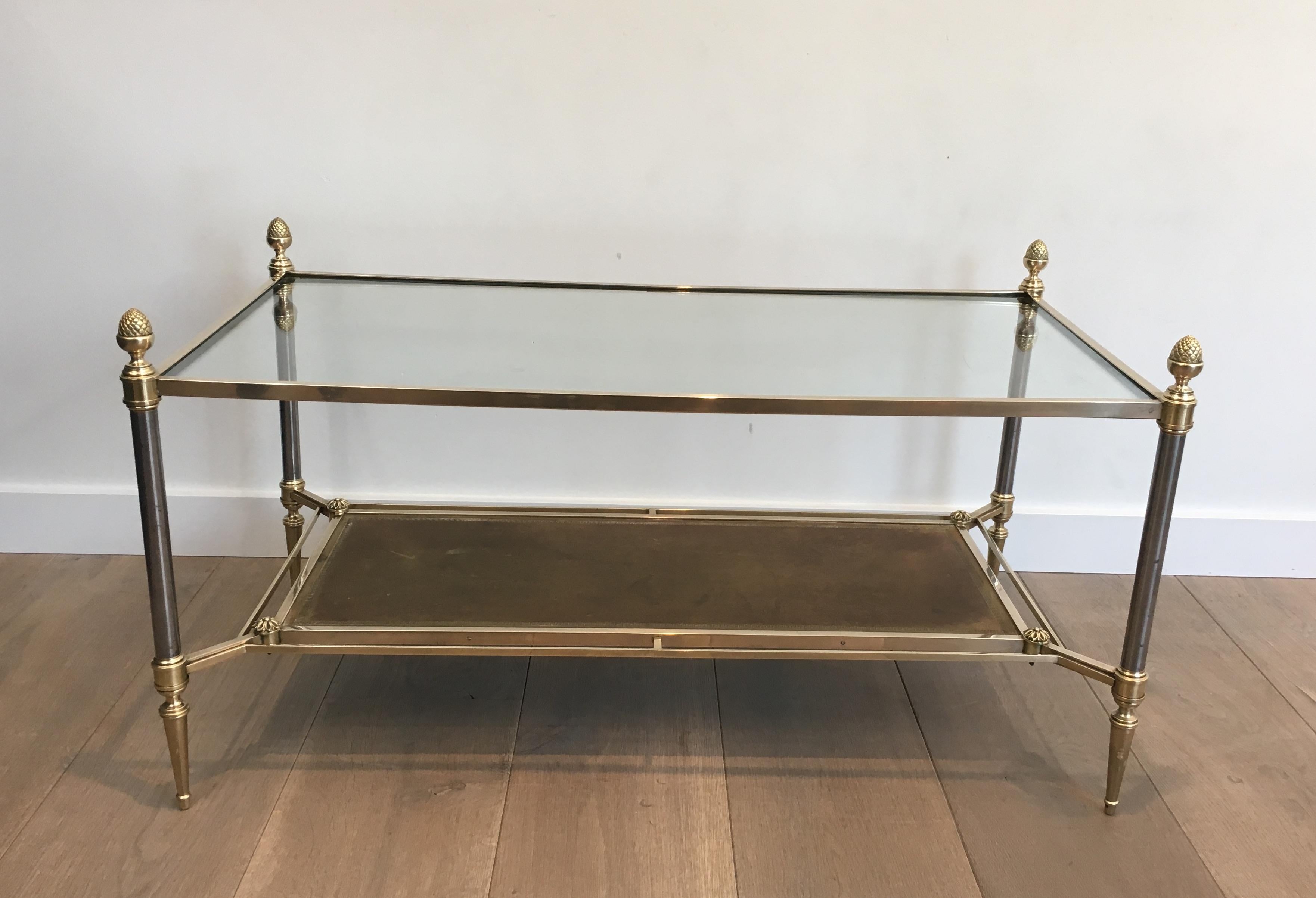 This neoclassical coffee table is made of brass and brushed steel with glass on top shelf and leather on bottom shelf. This is a very nice cocktail table of very good quality. This is a French work by famous designer Maison Jansen, circa 1970.