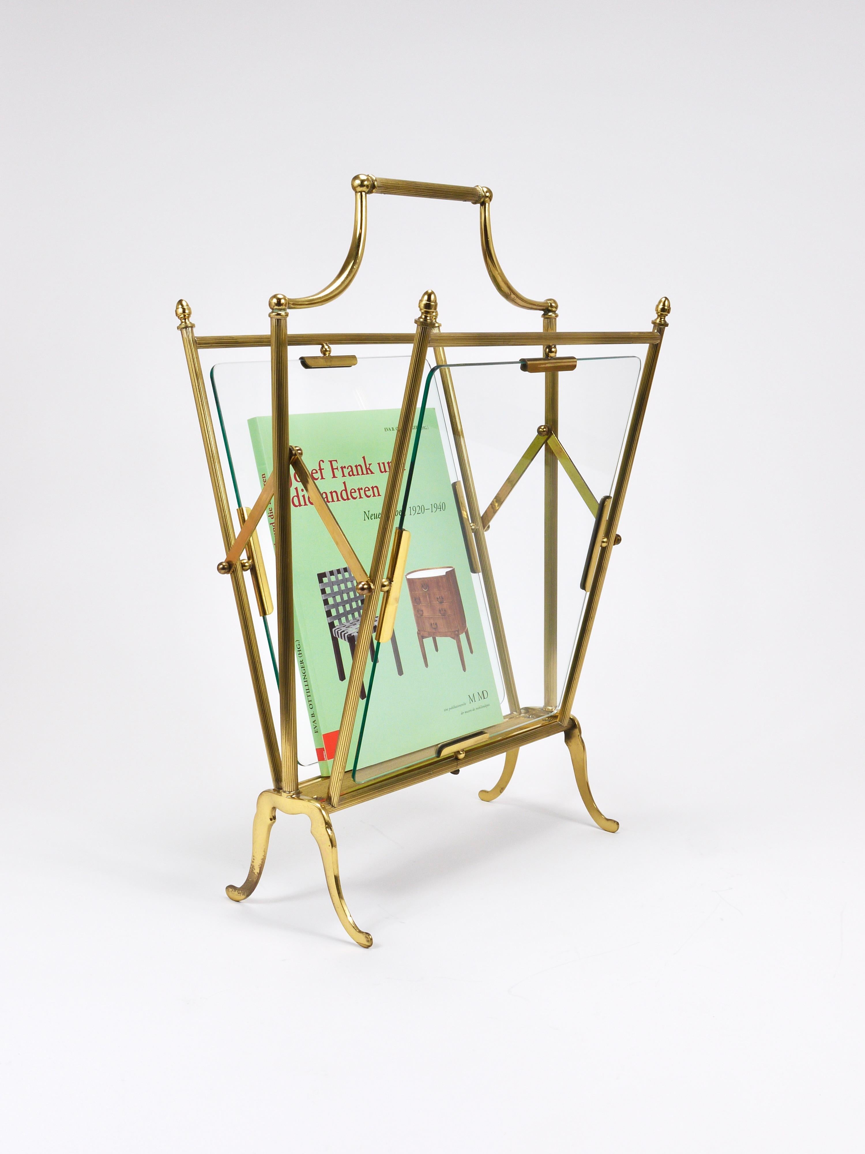A French Hollywood Regency-style news rack, magazine stand, or book holder, crafted by Maison Jansen in the 1960s. Elegantly constructed from solid polished brass and clear glass, tit showcases the sophistication typical of the era. Both functional