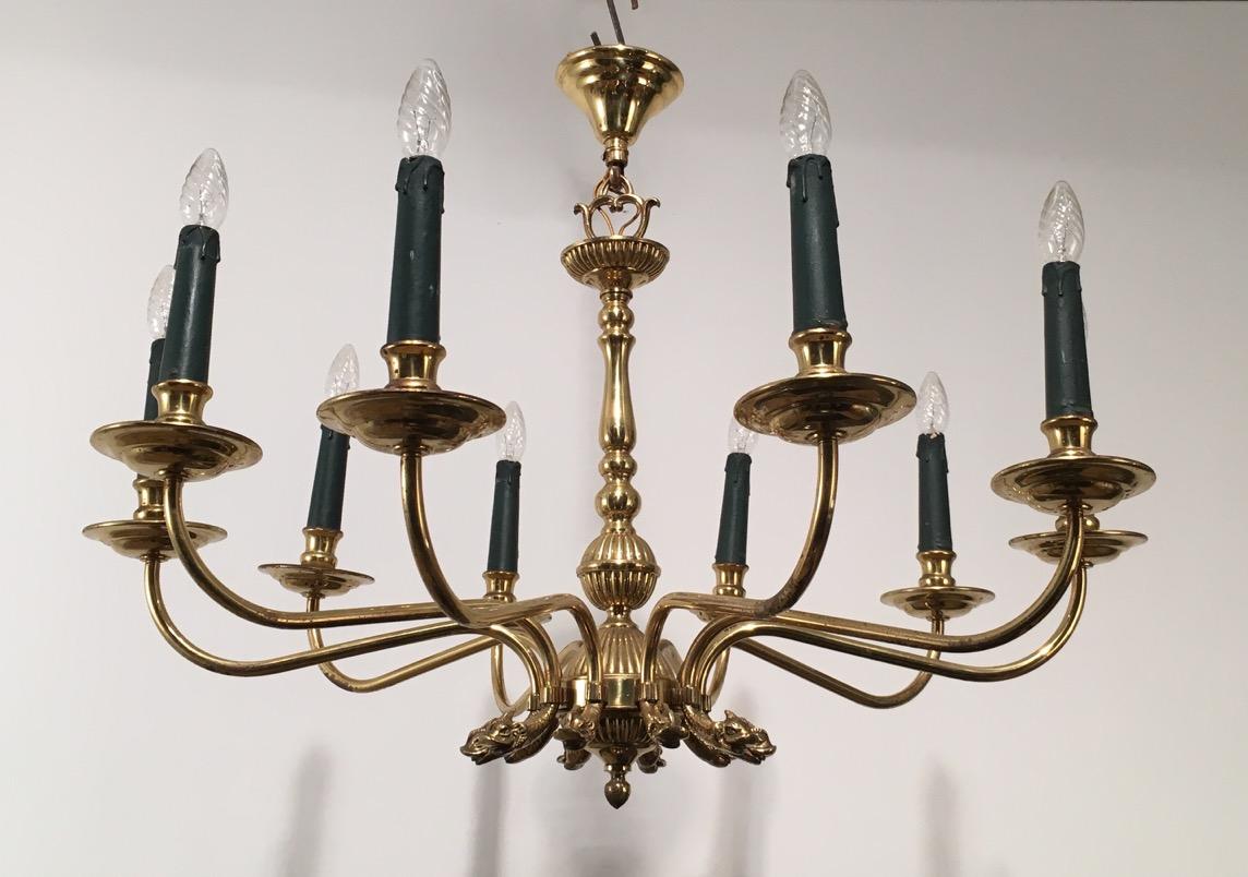 This neoclassical style chandelier is made of brass. This is a very elegant and decorative 10-light fixture with dolfin heads. This is a work by famous French Designer Maison Jansen, circa 1940.