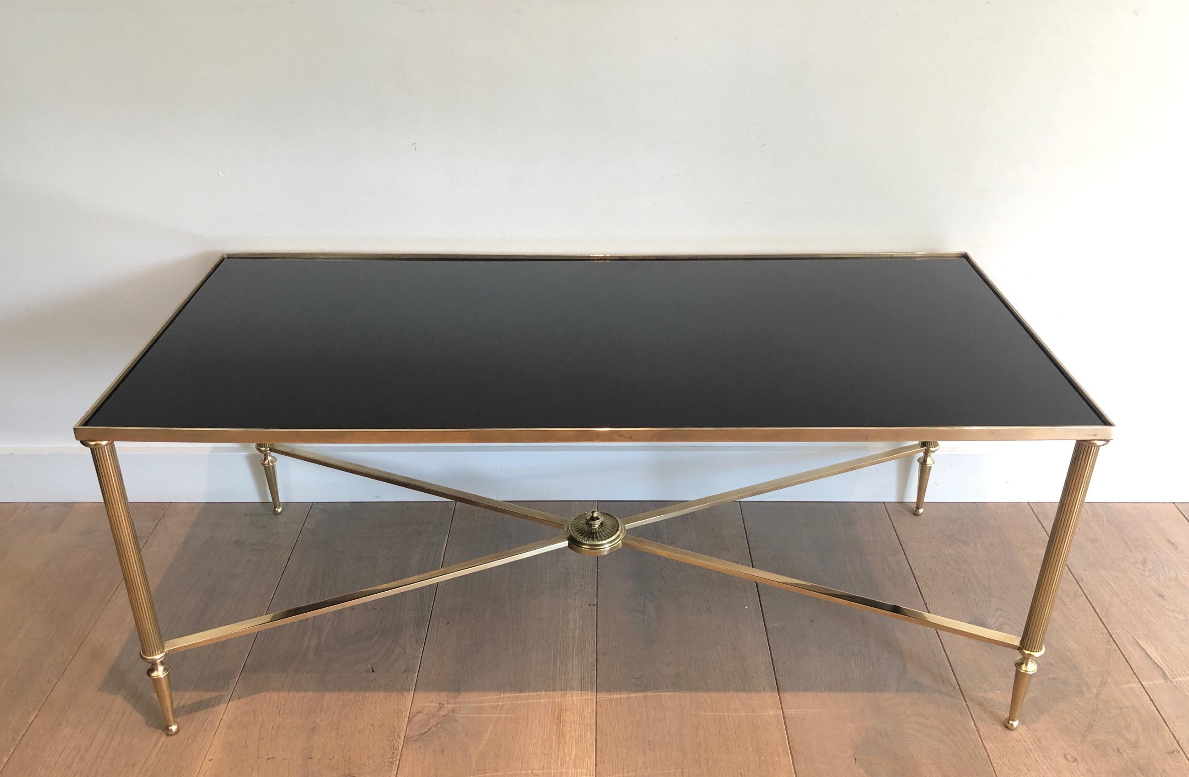 This neoclassical style coffee table is made of brass with a black lacquered glass top. This is a work by famous French designer Maison Jansen, circa 1940.