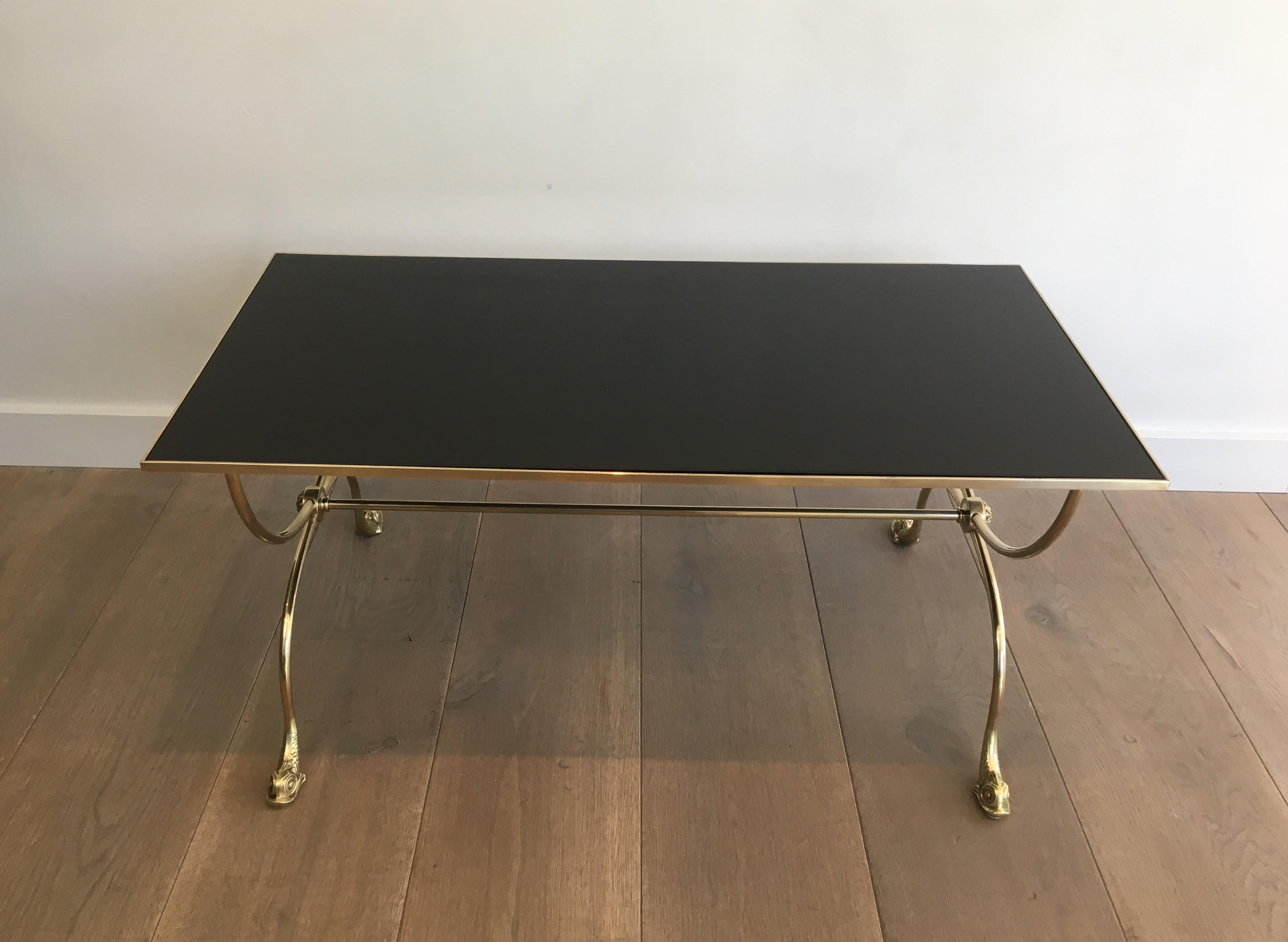 This beautiful neoclassical style coffee table is made of brass with dolphin heads and a black lacquered glass shelf. This is a very elegant and decorative work by famous French designer Maison Jansen, circa 1940.