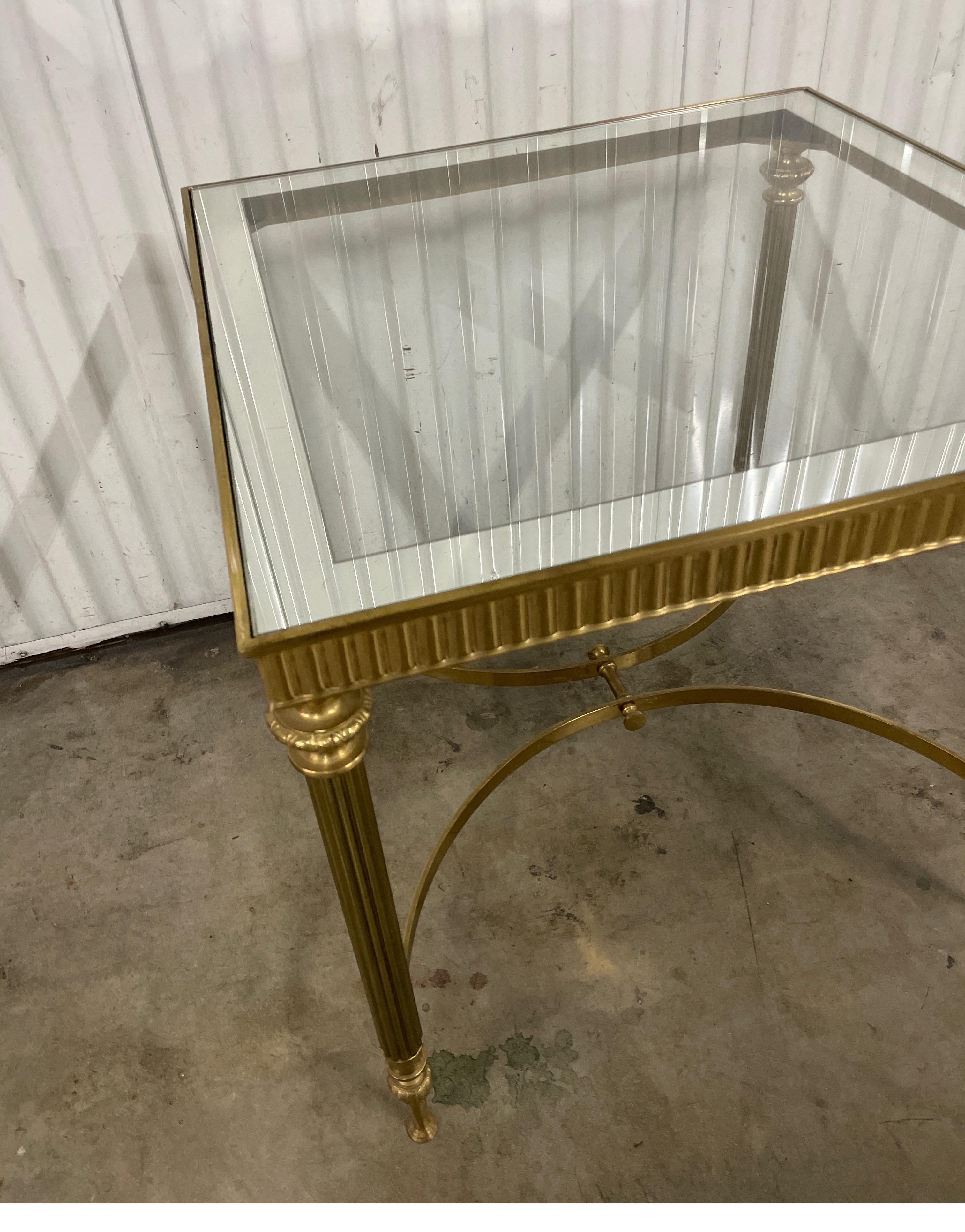 Neoclassical style brass square side table by Maison Jansen. The top is glass with a mirrored border surround. All four legs are connected with brass stretchers. Legs and top surround are all fluted.