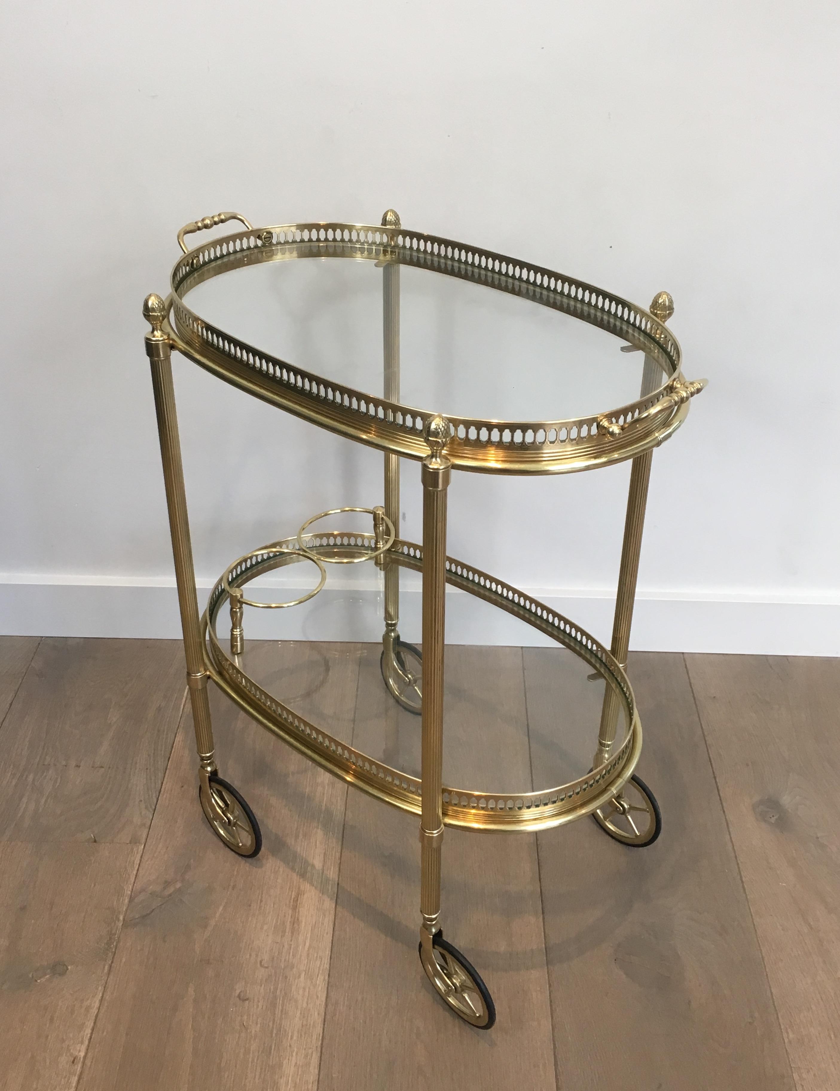 This very nice neoclassical style oval bar cart is made of brass with clear glass shelves. This drinks trolley is very delicate with a Fine gallery surrounded the glass shelves. It has 2 removable trays. This is a nice work by famous French designer