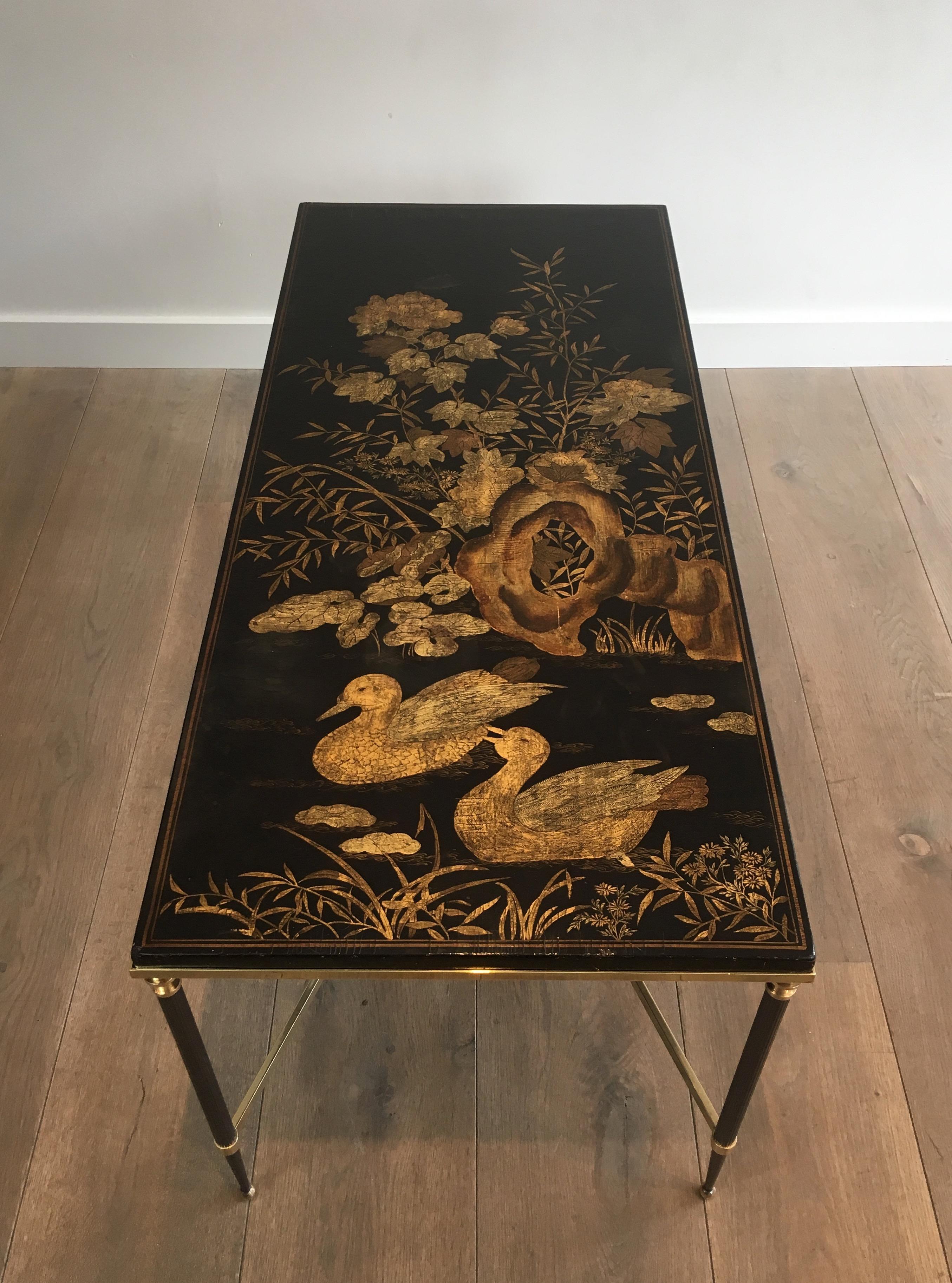 This beautiful neoclassical coffee table is made of a gun metal and brass base supporting a very nice black and gilt lacquered wooden top. This fine lacquered top showing two ducks swimming together in a gilt floral decor. This piece is a work by