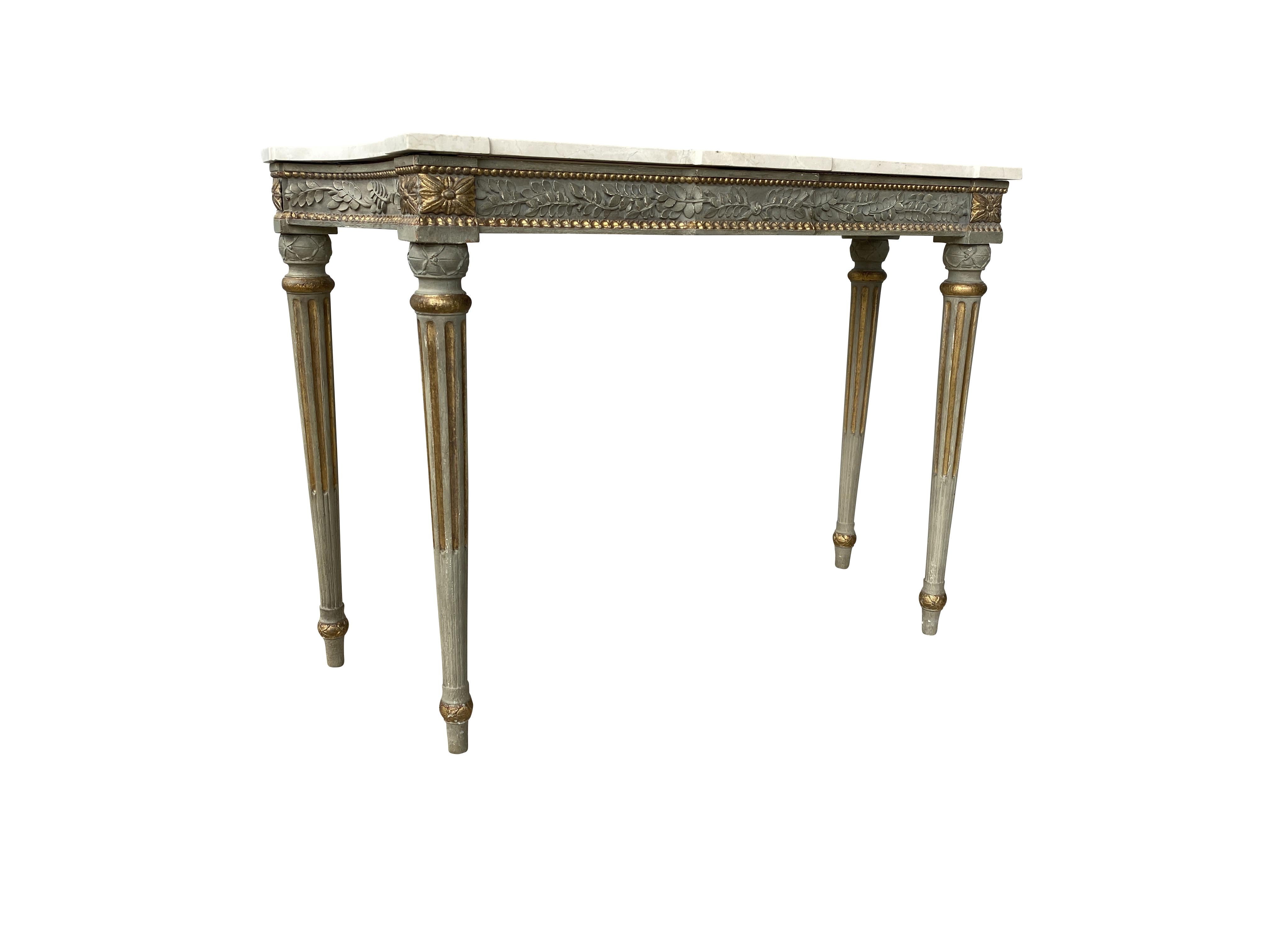 With rectangular marble top with curved ends over a conforming frieze carved with laurel leaves and beading, raised on circular tapered stop fluted legs. Provenance: Waldorf Towers New York. With label.
