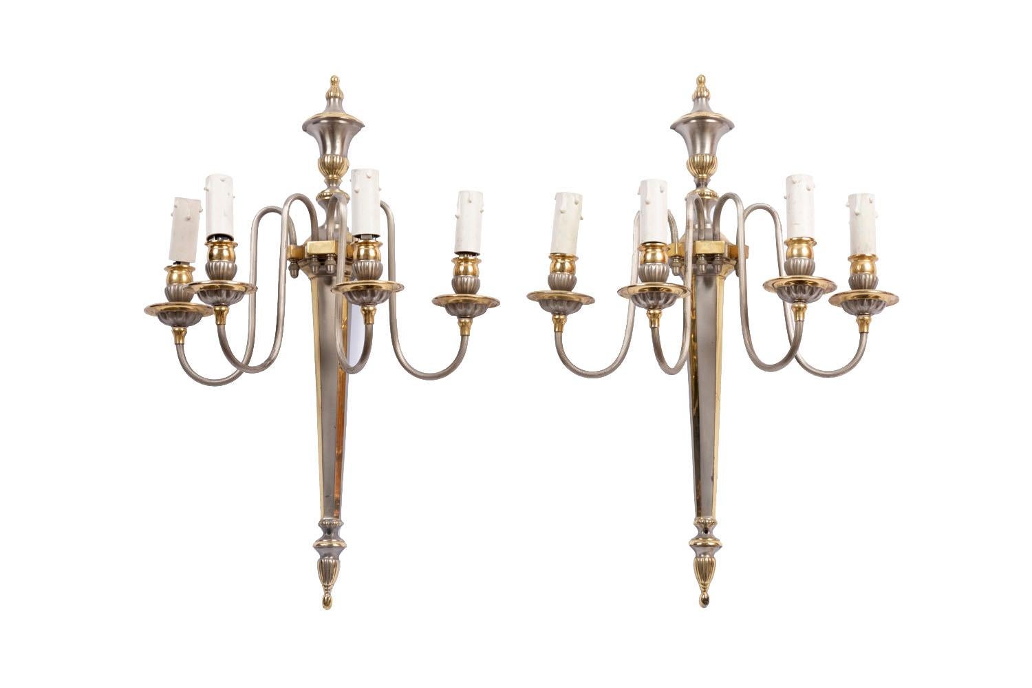 Maison Jansen, en el gusto de.

Pareja de apliques de pared de latón dorado y plateado de estilo Directoire con luces de cuatro brazos. Fuste de chandelle rematado por un jarrón antiguo cubierto y rematado por un motivo estilizado de borla de